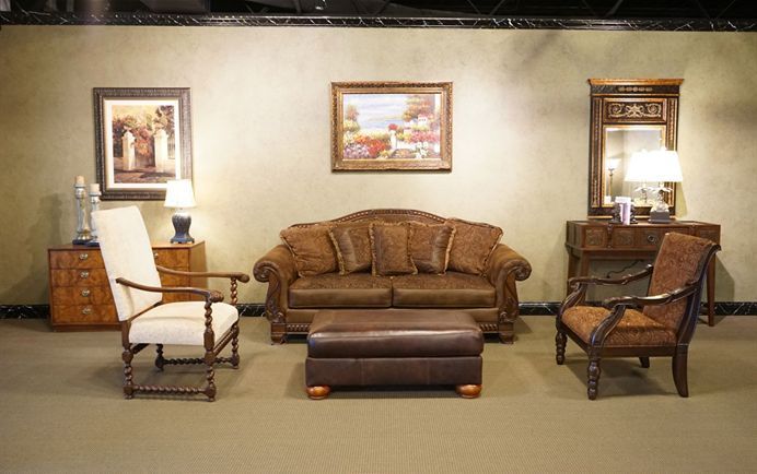 Elegant living room with brown sofa, two chairs, ottoman, mirrors, and framed wall art