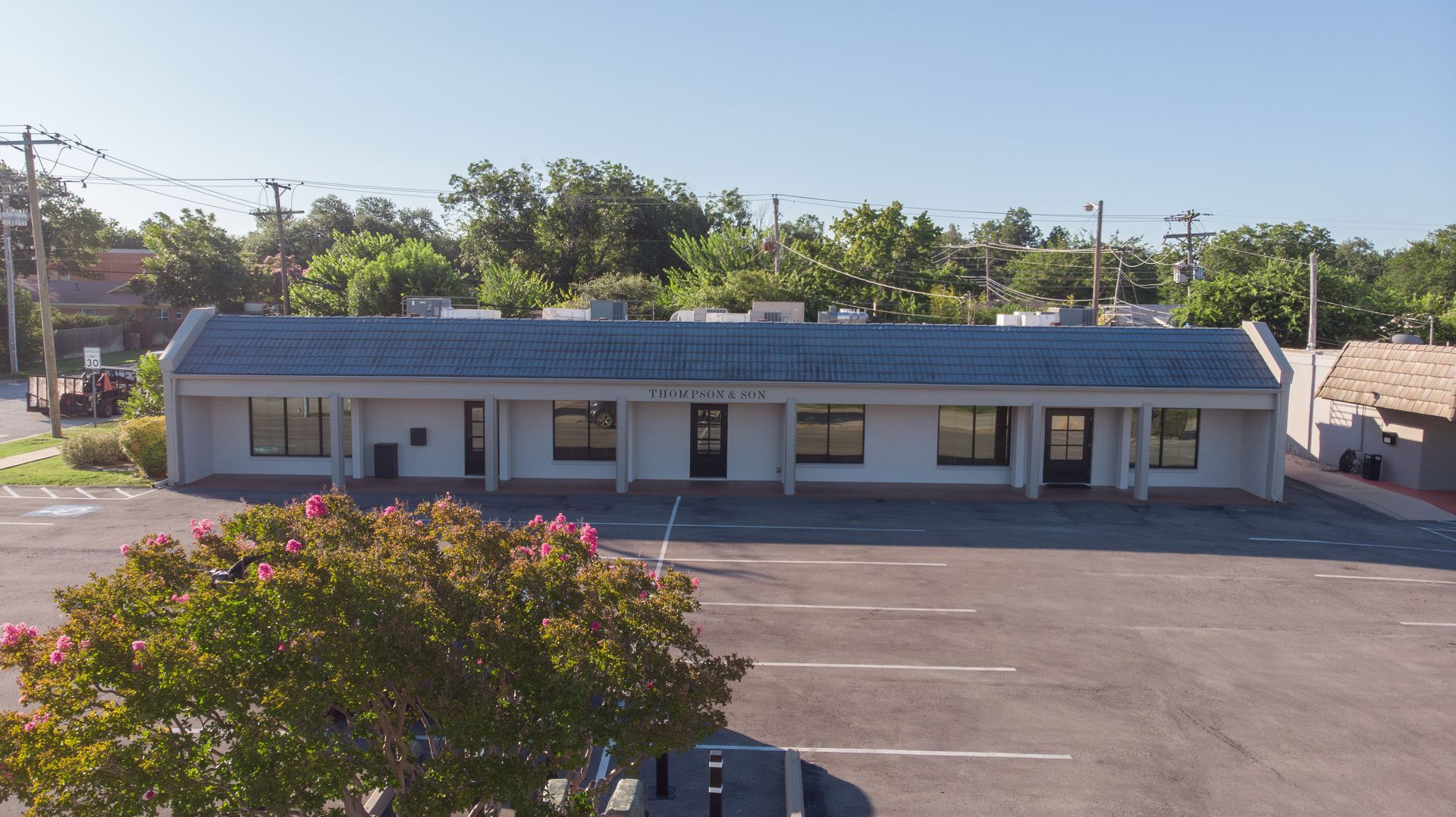 Single-story blue-roofed building with parking lot and trees in front