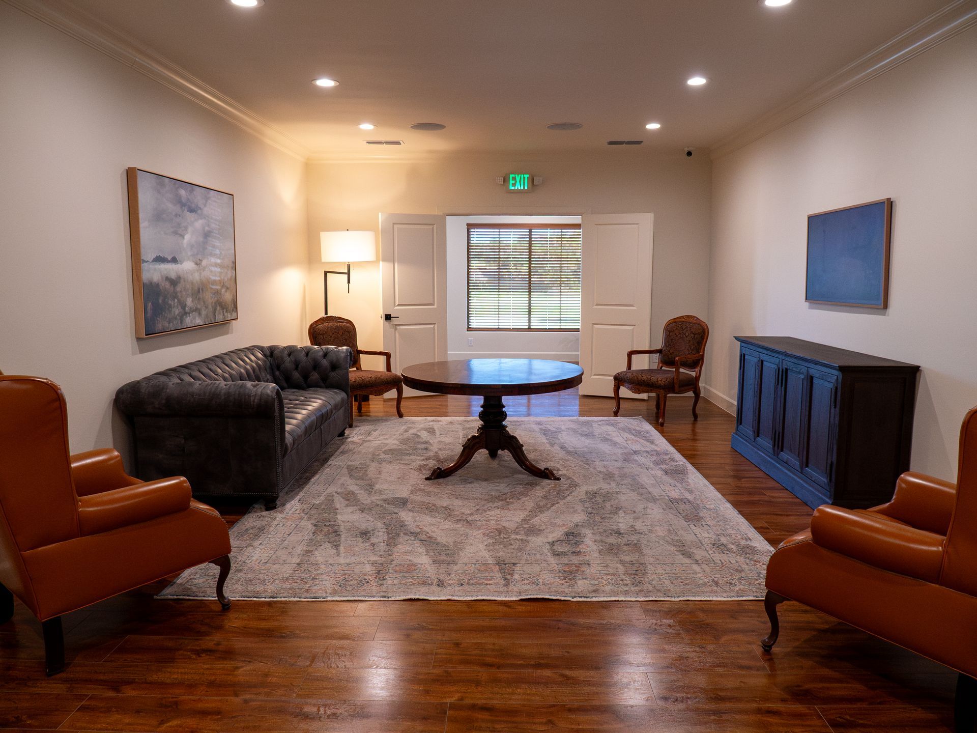 Cozy living room with sofa, armchairs, rug, coffee table, and framed wall art under recessed lighting