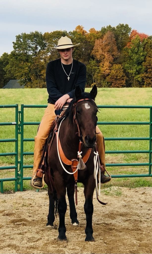 A man in a cowboy hat is riding a horse in a field