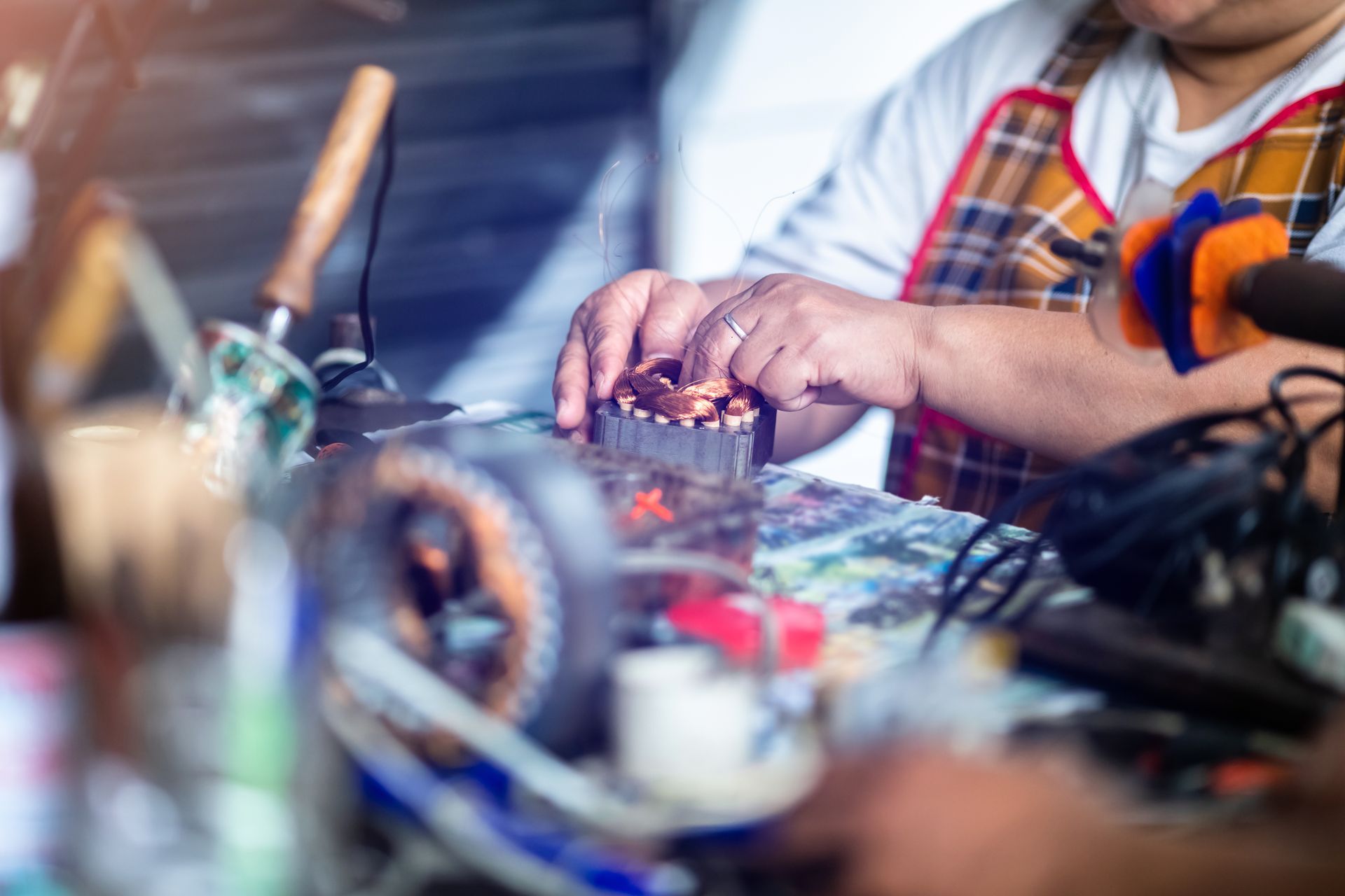 Mechanic is repairing an electric motor by replacing the copper coil. Mechanic is repairing an electric motor by replacing the copper coil.
