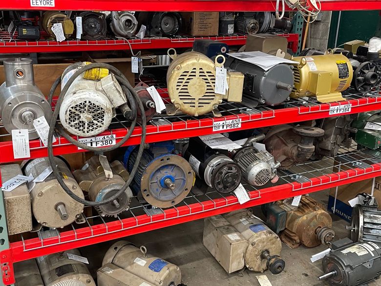 A warehouse shelf filled with various industrial electric motors of different sizes, colors, and shapes.