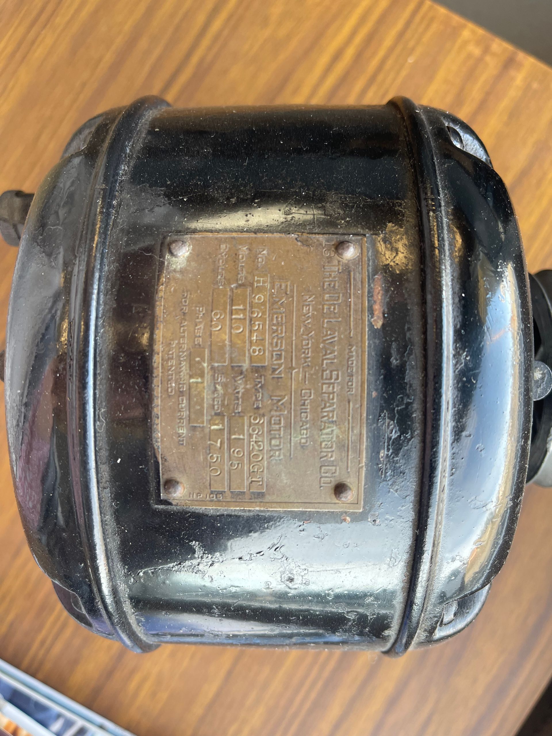 A shiny black electric motor housing with a metallic nameplate attached to its top surface.