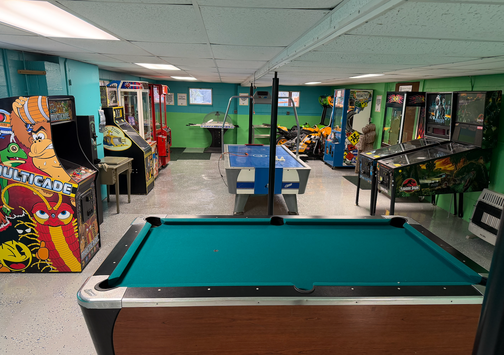 Air hockey table in a brightly lit arcade with other games.