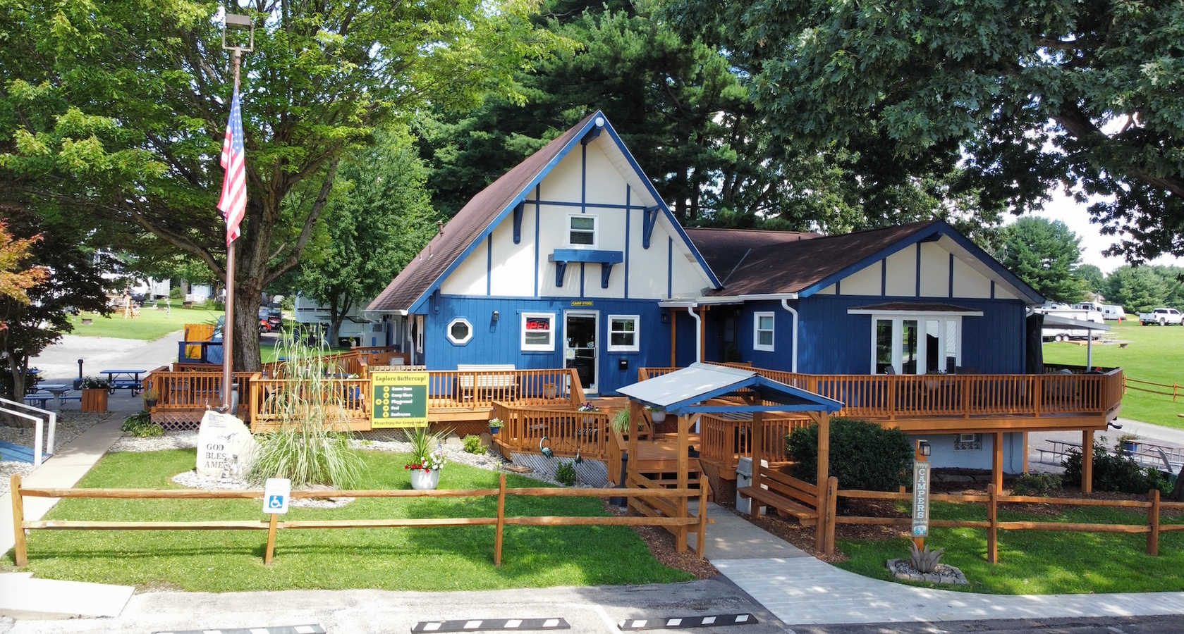 Blue and white building with a wooden deck, a golf cart, and an American flag.
