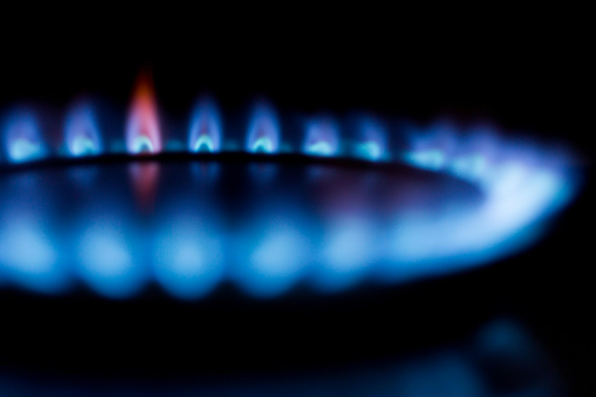 Blue flames burning on a black background, likely a gas stove burner.