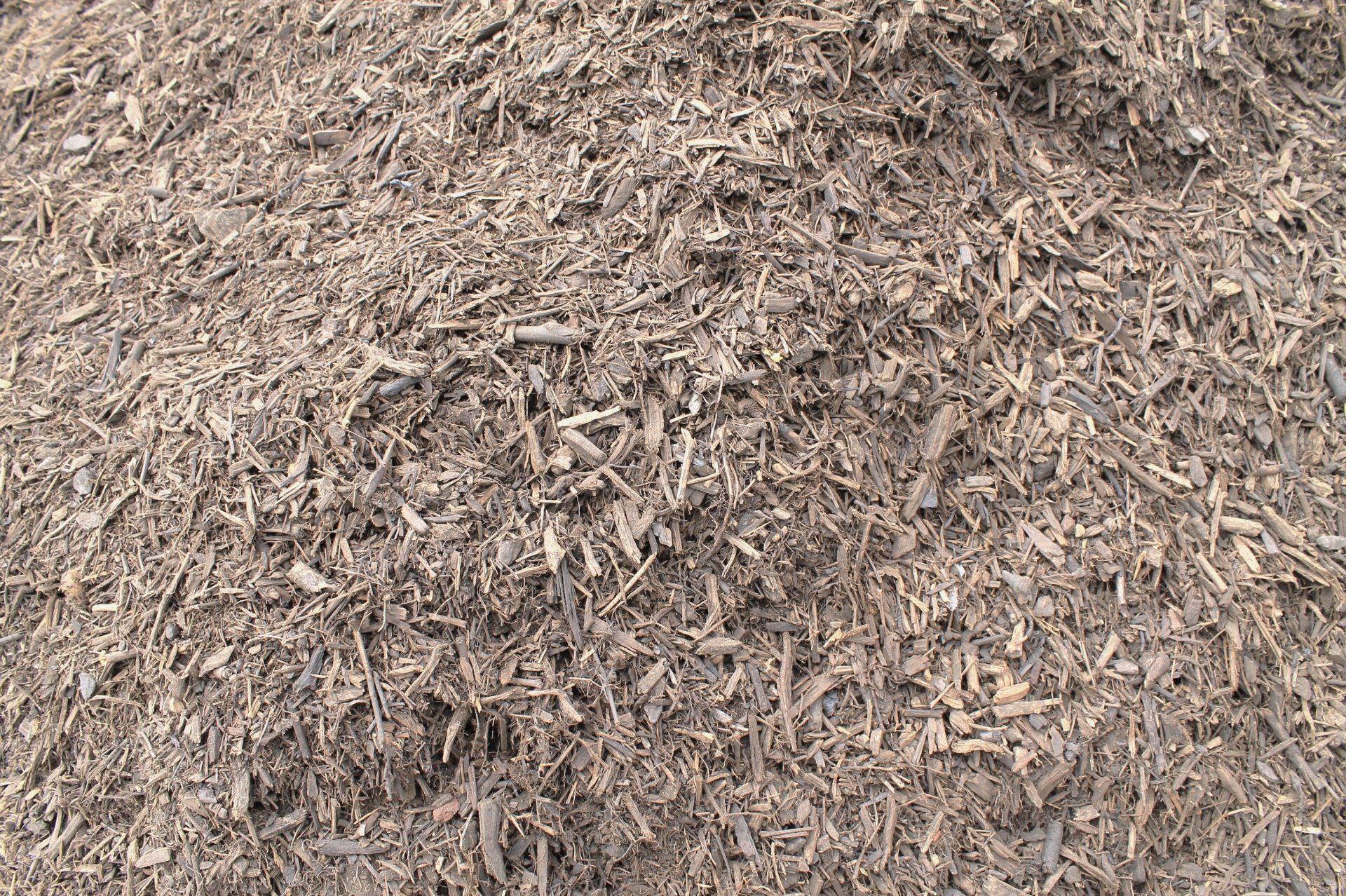 Pile of brown wood mulch, consisting of shredded wood pieces, likely for landscaping.