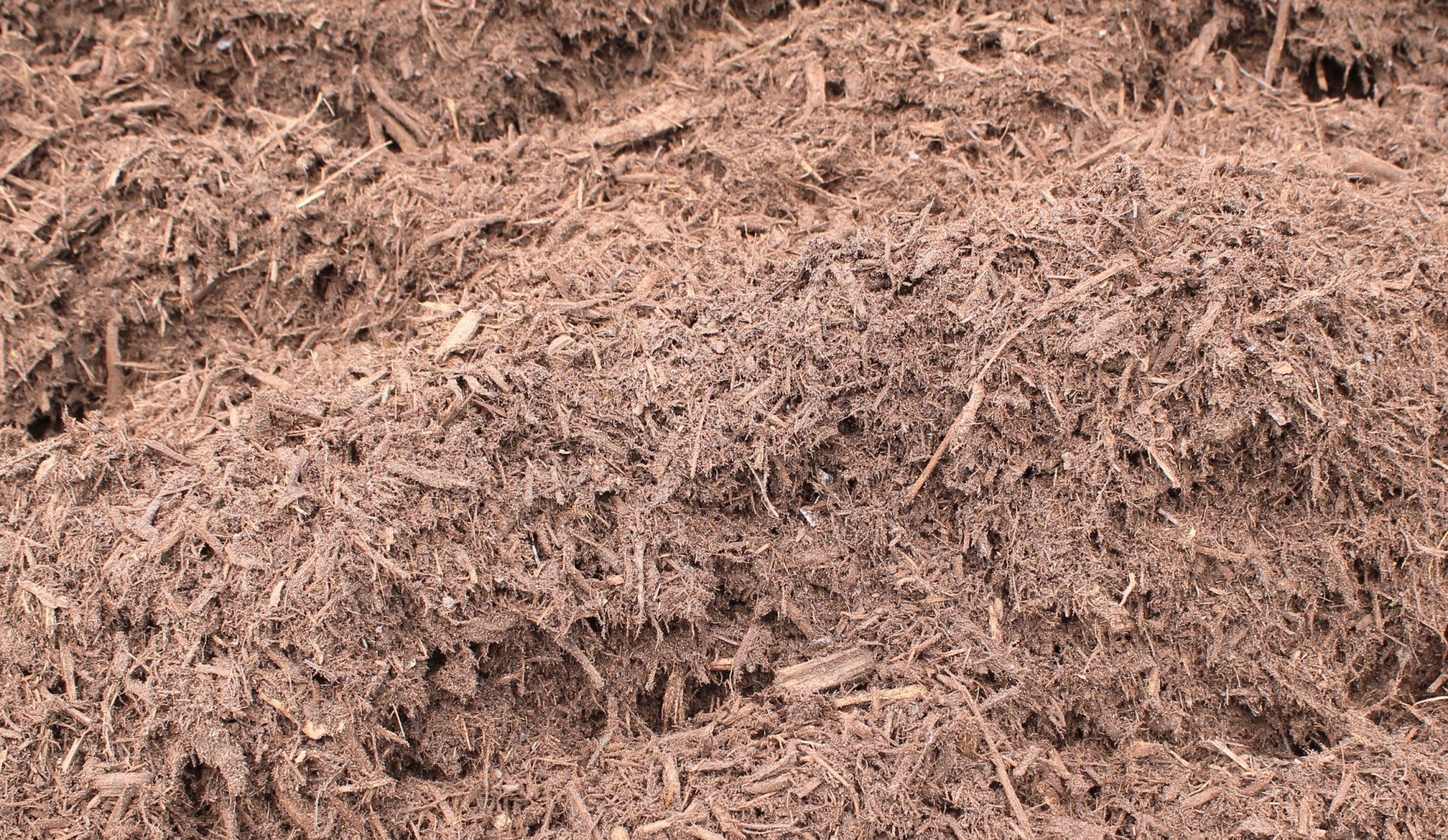 Brown mulch, textured and shredded, covering an area.
