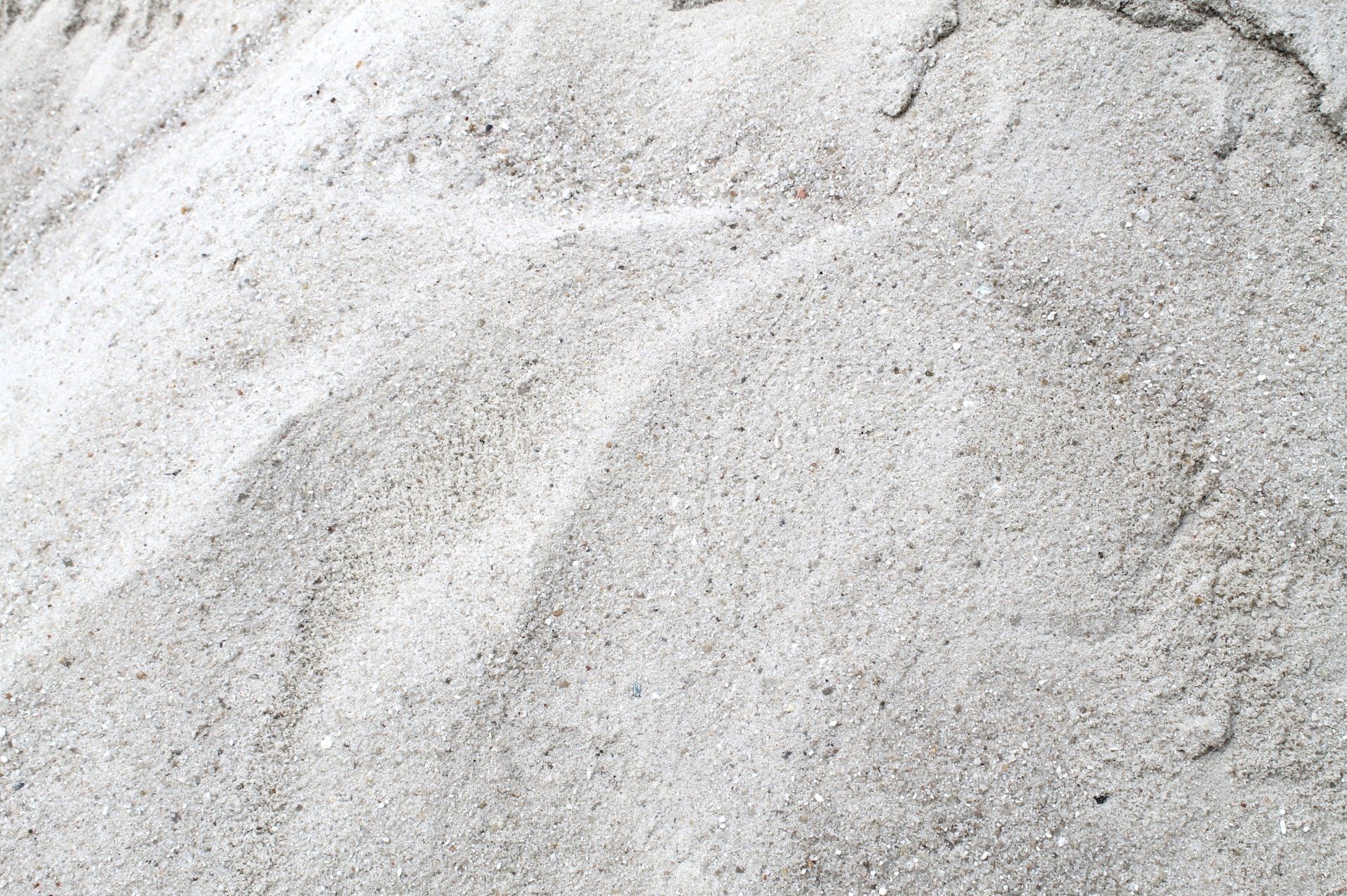 Close-up view of light-colored sand, with small, granular texture.