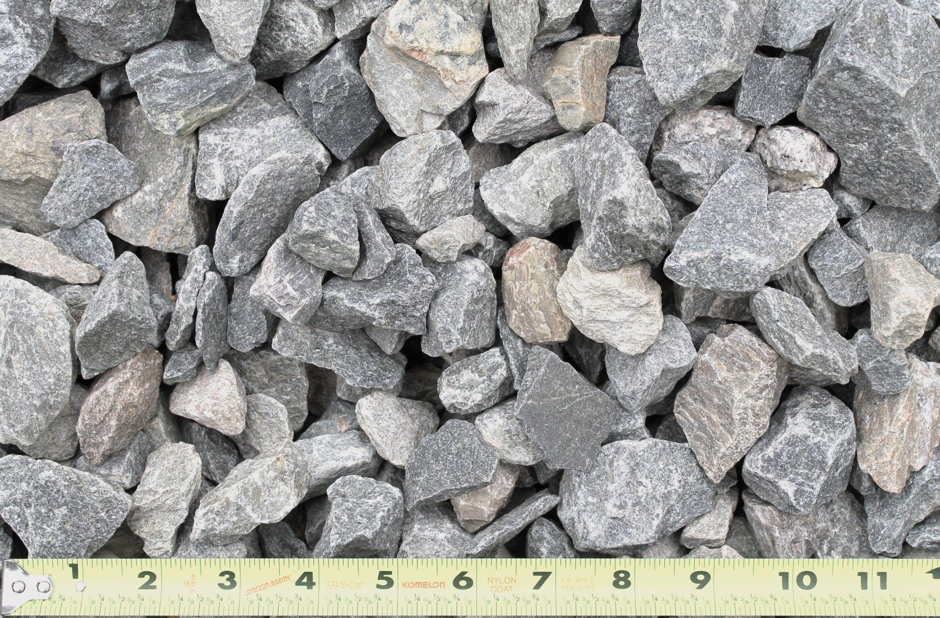 Crushed gray and tan gravel rocks with a ruler for scale.