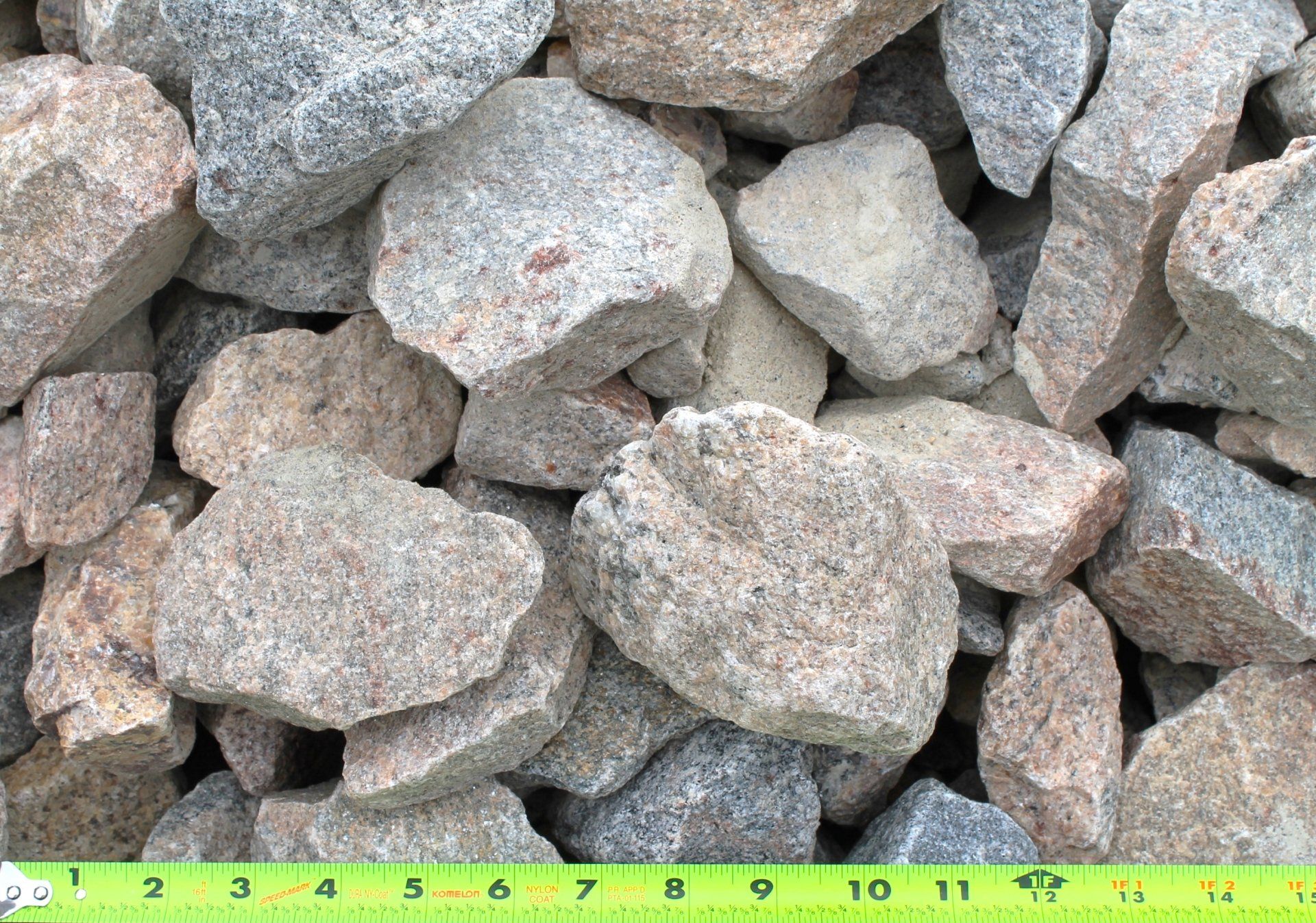 Rough, multi-colored rocks of various sizes, with a green and yellow ruler along the bottom.