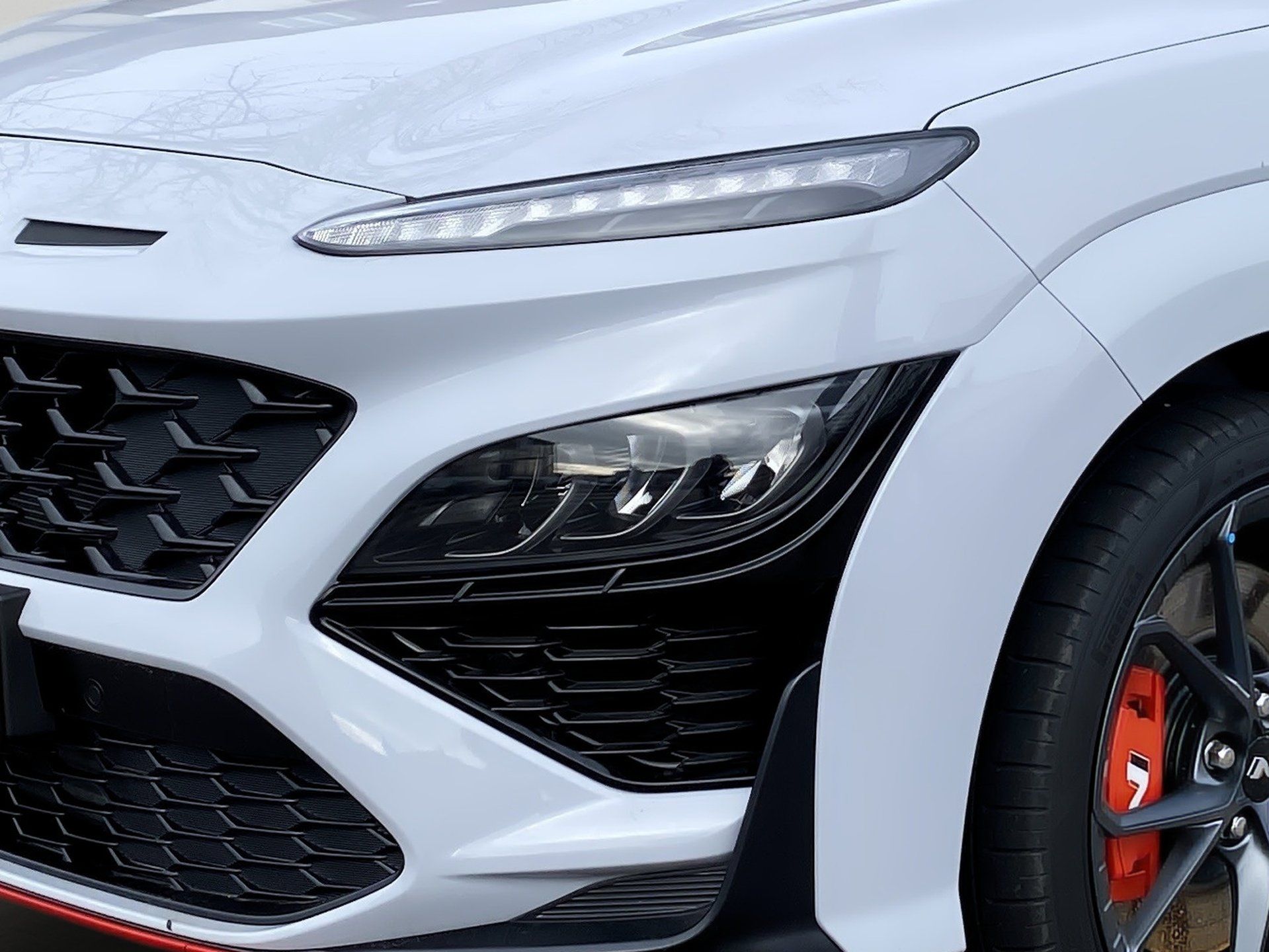 Front view of a white sports car with black grille and orange brake caliper
