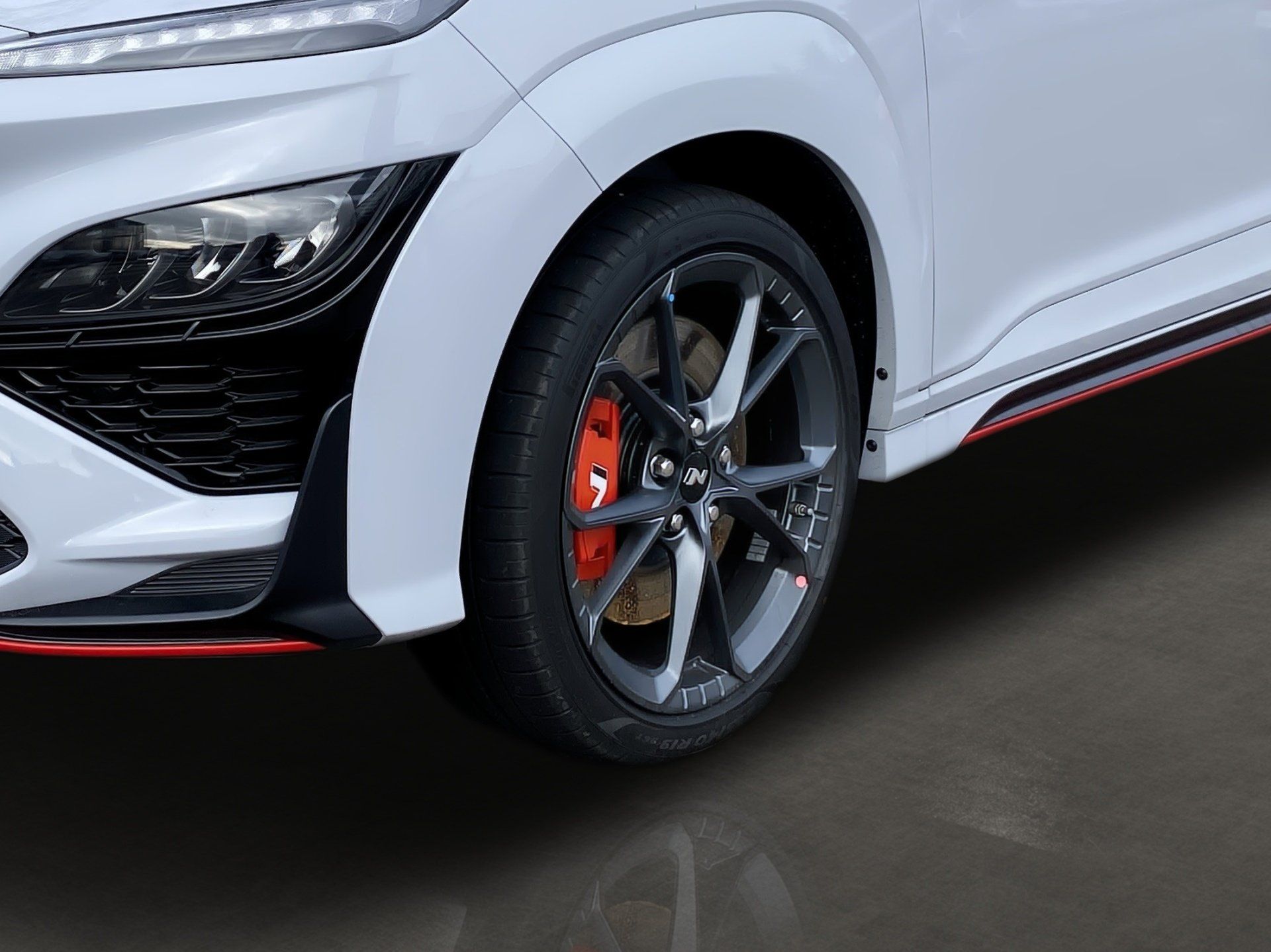 Close-up of a white sports car front wheel with black rims and red brake caliper