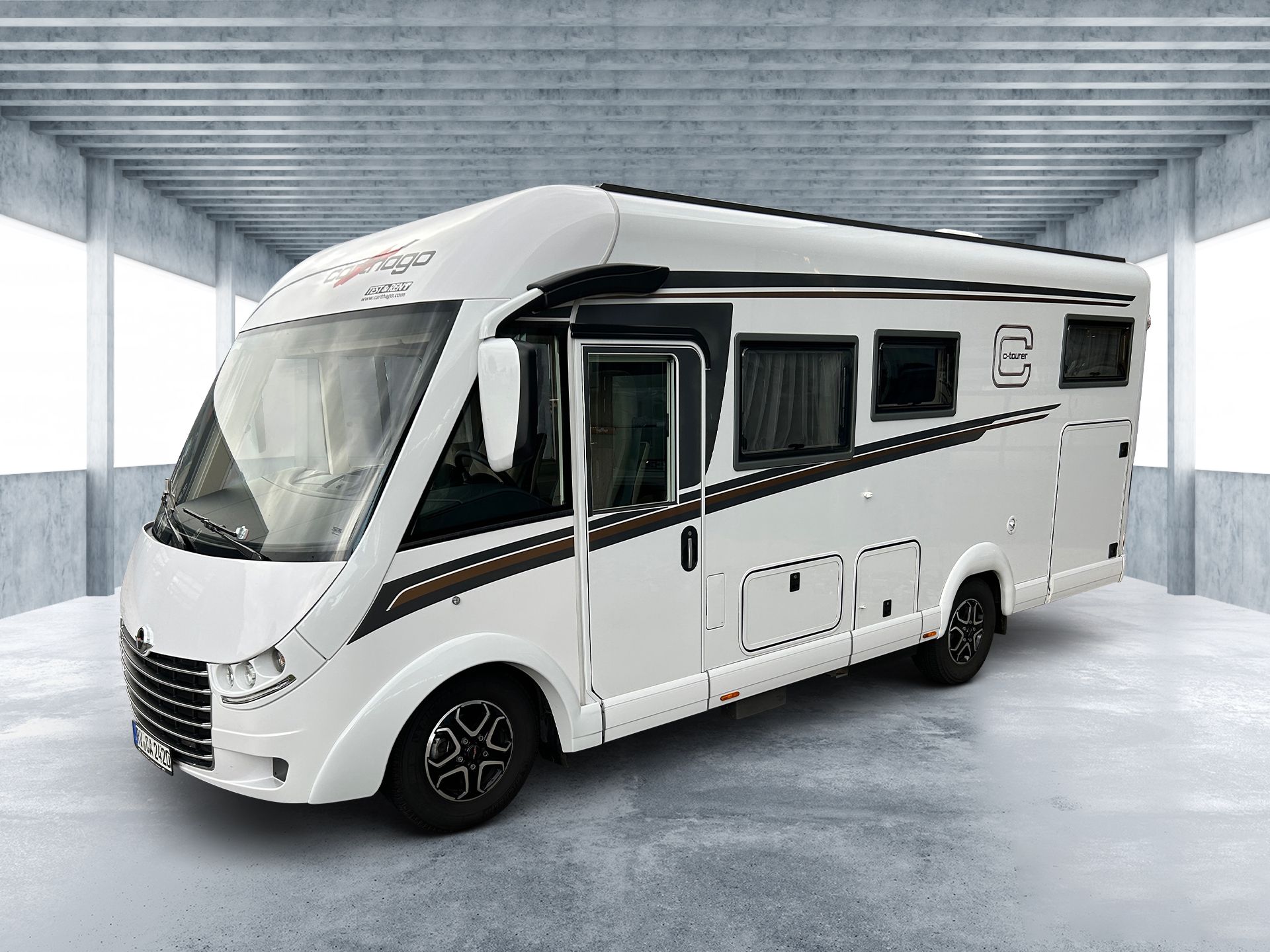 Biely obytný automobil zaparkovaný v interiéri vo svetlom priestore podobnom garáži