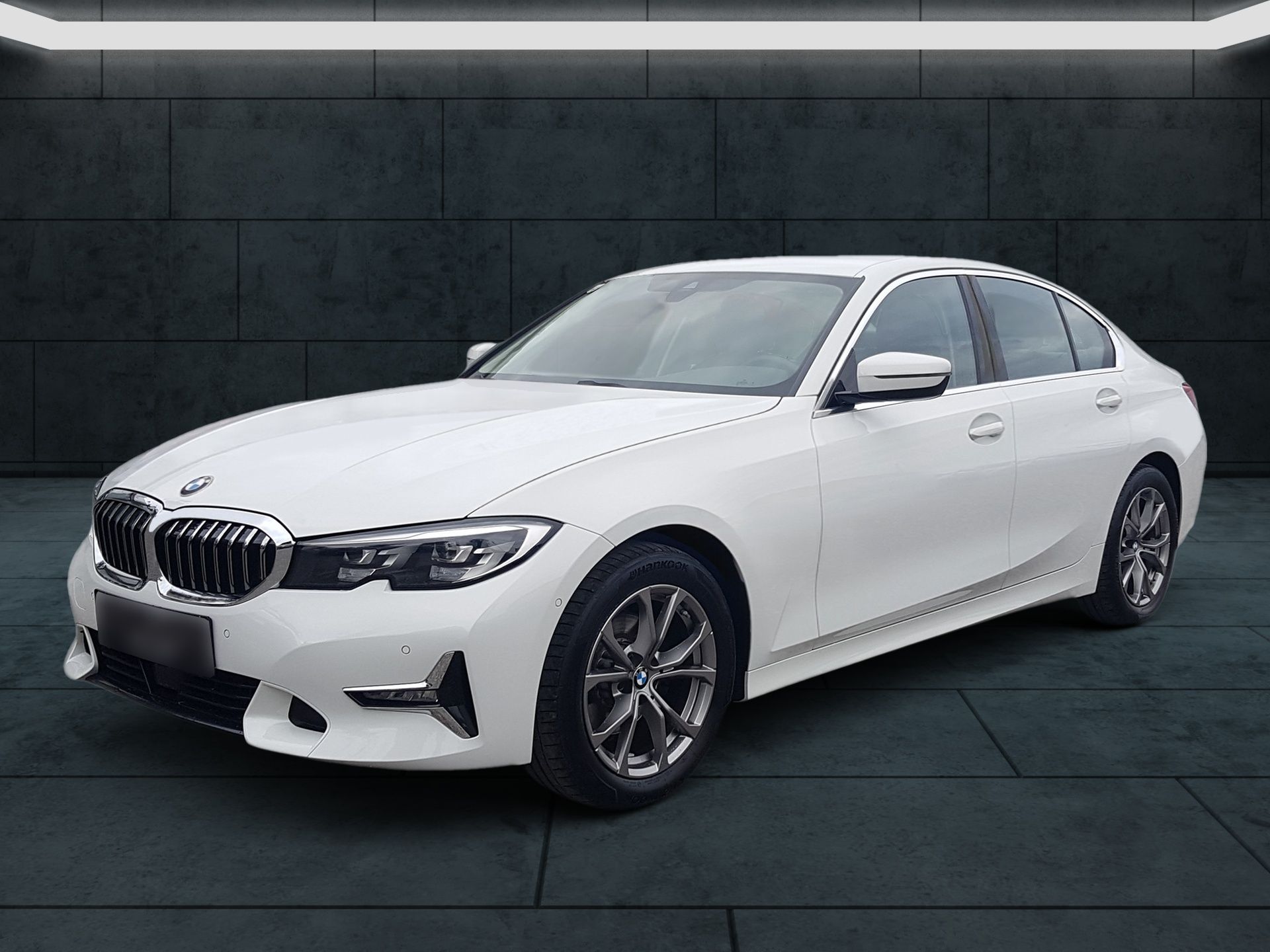 White BMW sedan in a studio setting, shown from the front-left angle.