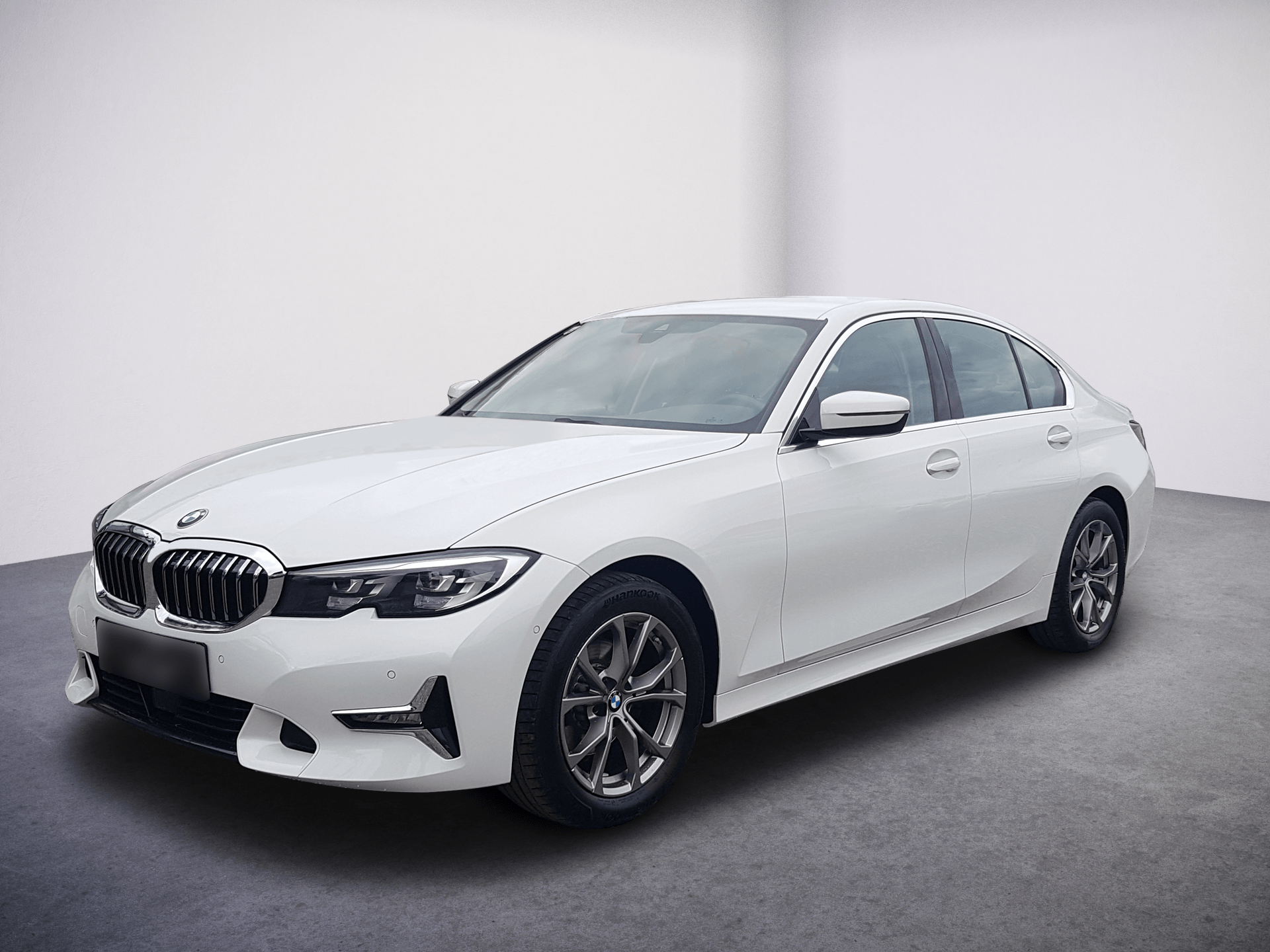 White BMW sedan in a studio, front-left view on a gray floor against a light backdrop