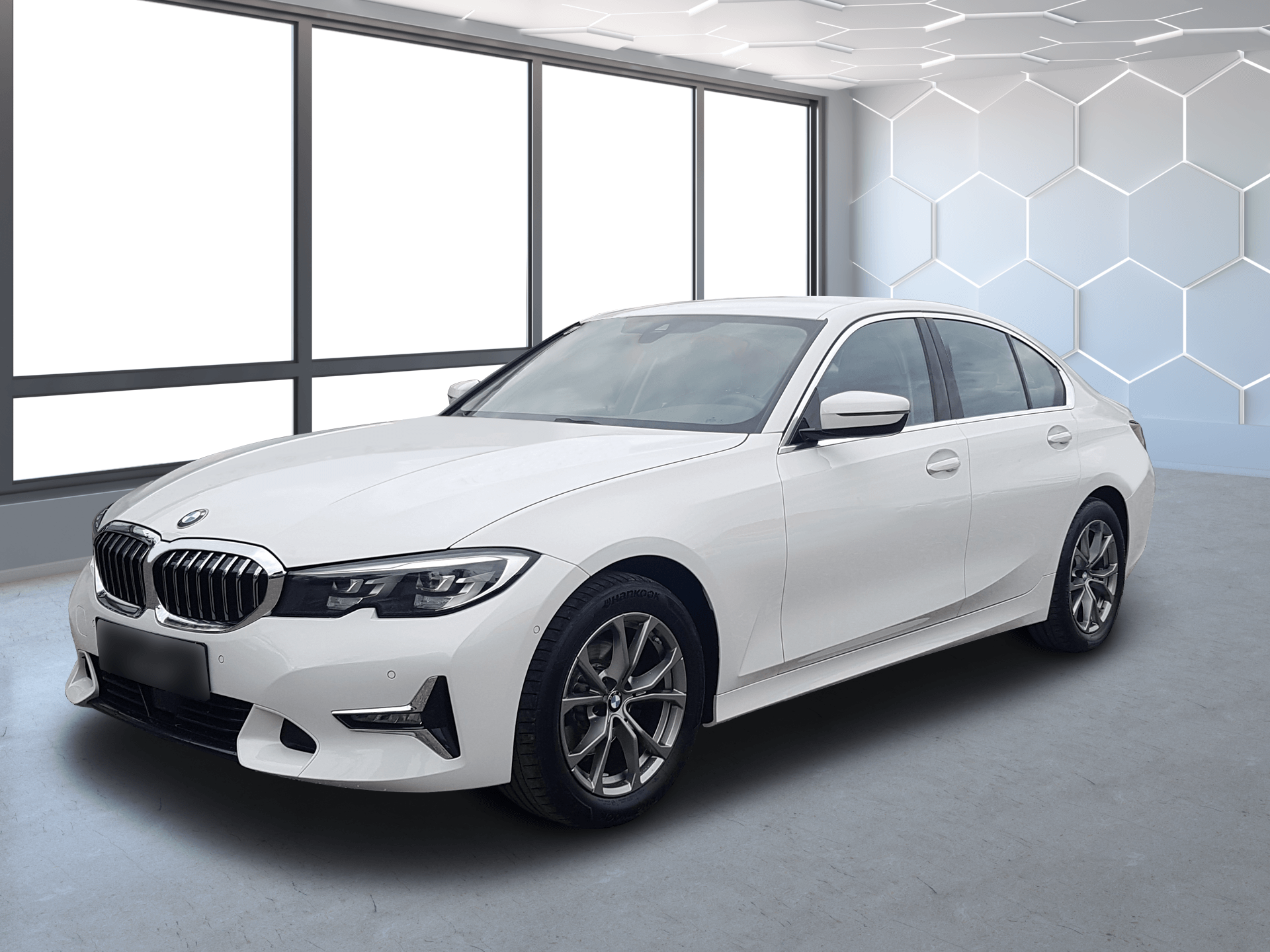 White BMW sedan in a bright showroom with large windows and a hexagon-patterned wall