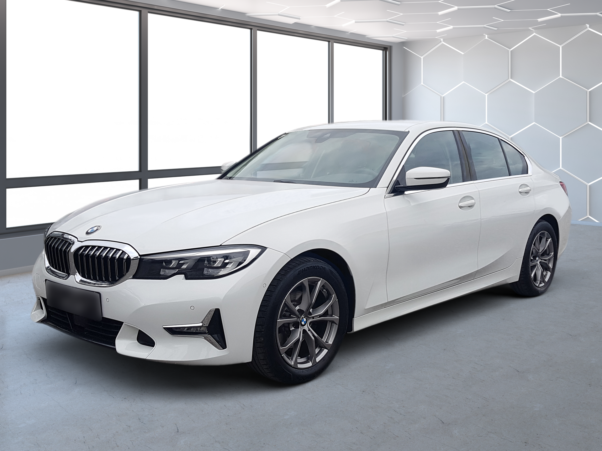 White BMW sedan in a studio with large windows and a hexagon-pattern wall