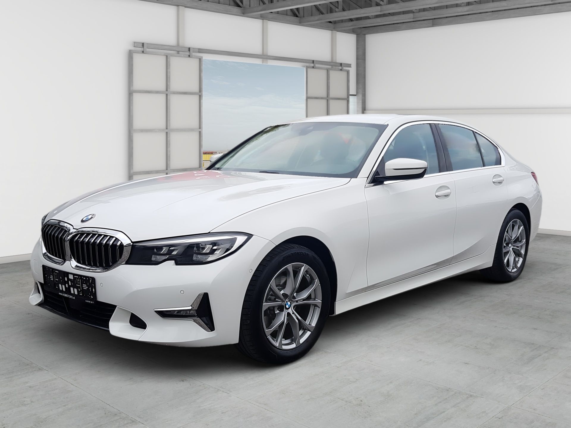 White BMW sedan parked in a bright showroom, front-left view