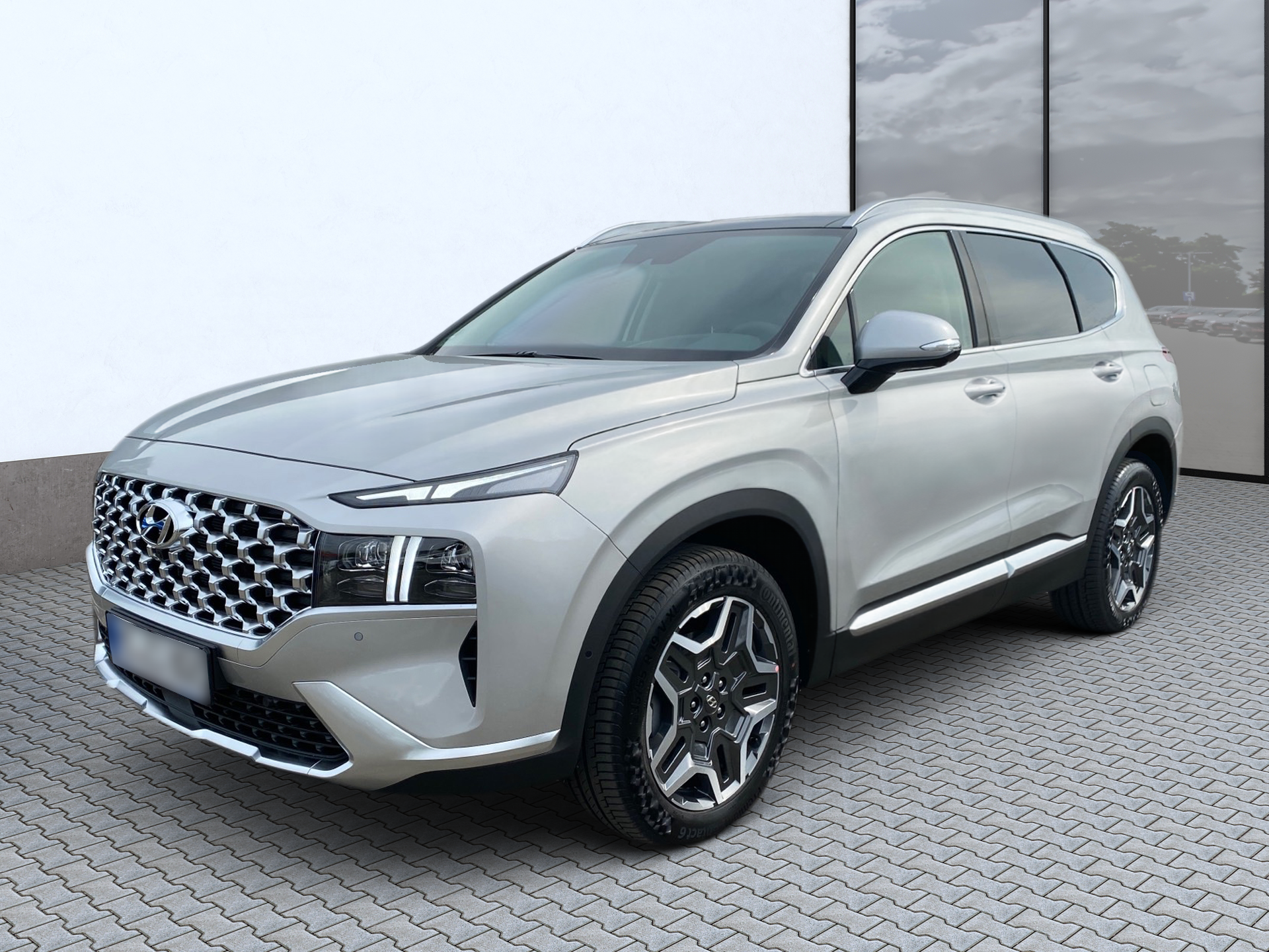 Strieborné SUV zaparkované na spevnenom parkovisku vedľa presklenej budovy.