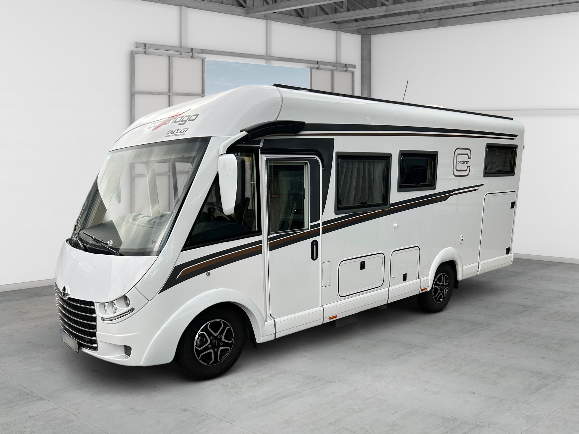 Biely obytný automobil zaparkovaný v interiéri vo svetlom priestore podobnom skladu.