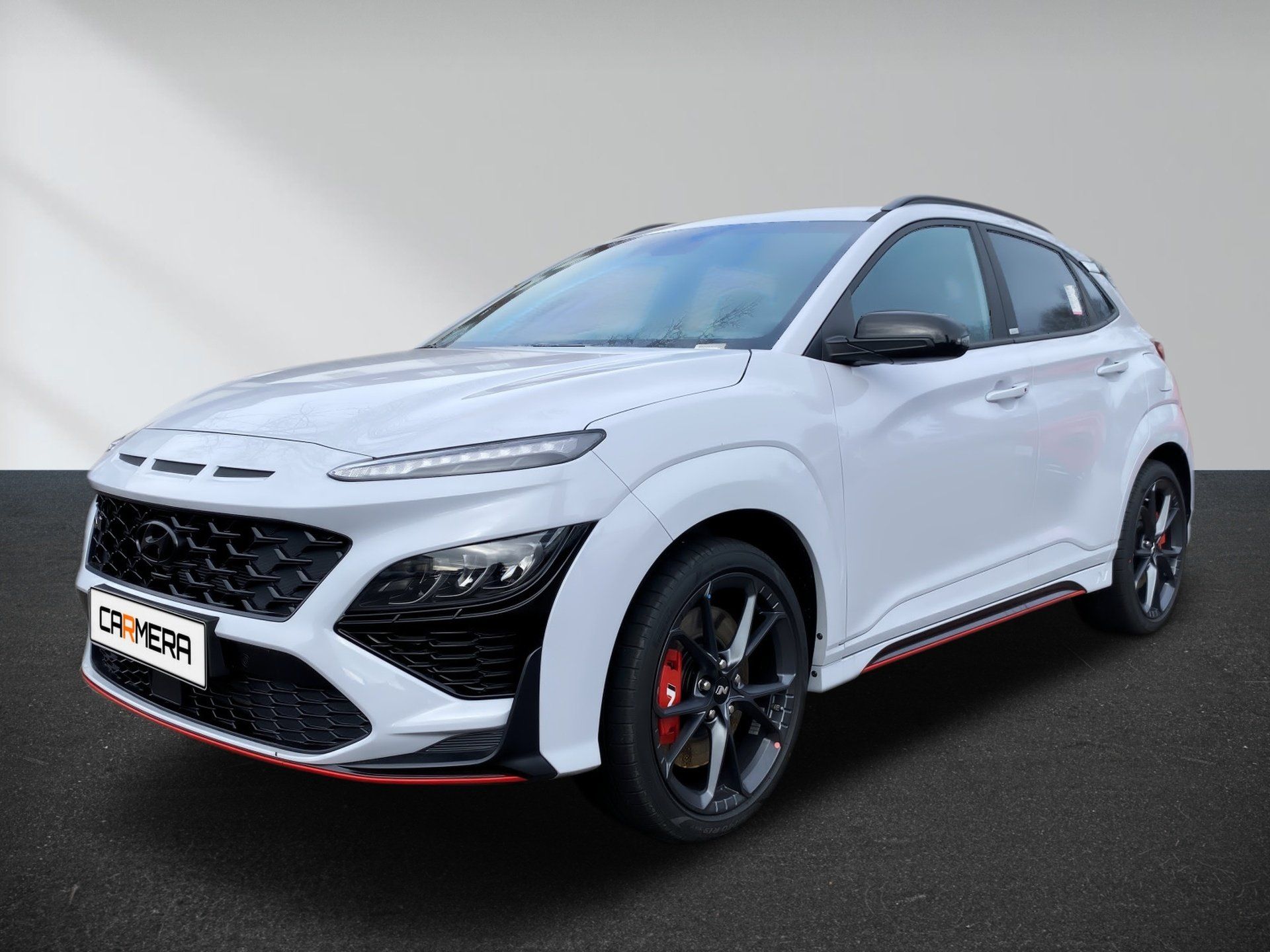 White sporty SUV on a studio background, angled front view with black rims and red accents