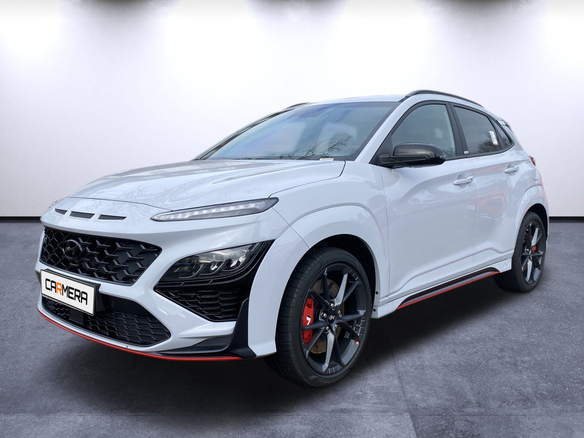White sporty crossover SUV with black accents and red trim, shown in a studio setting