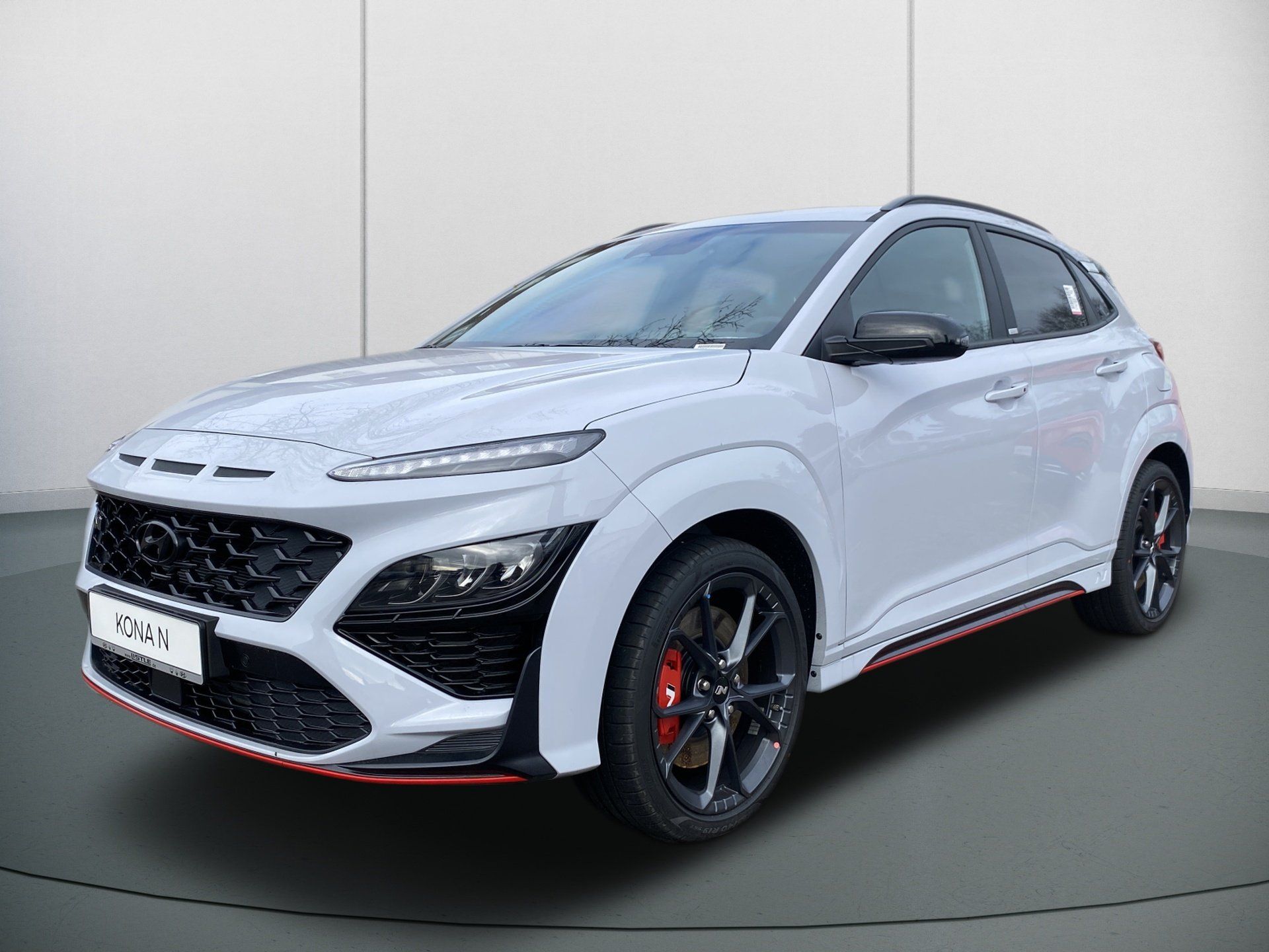 White sporty SUV with red accents and black wheels, shown in front three-quarter view indoors.