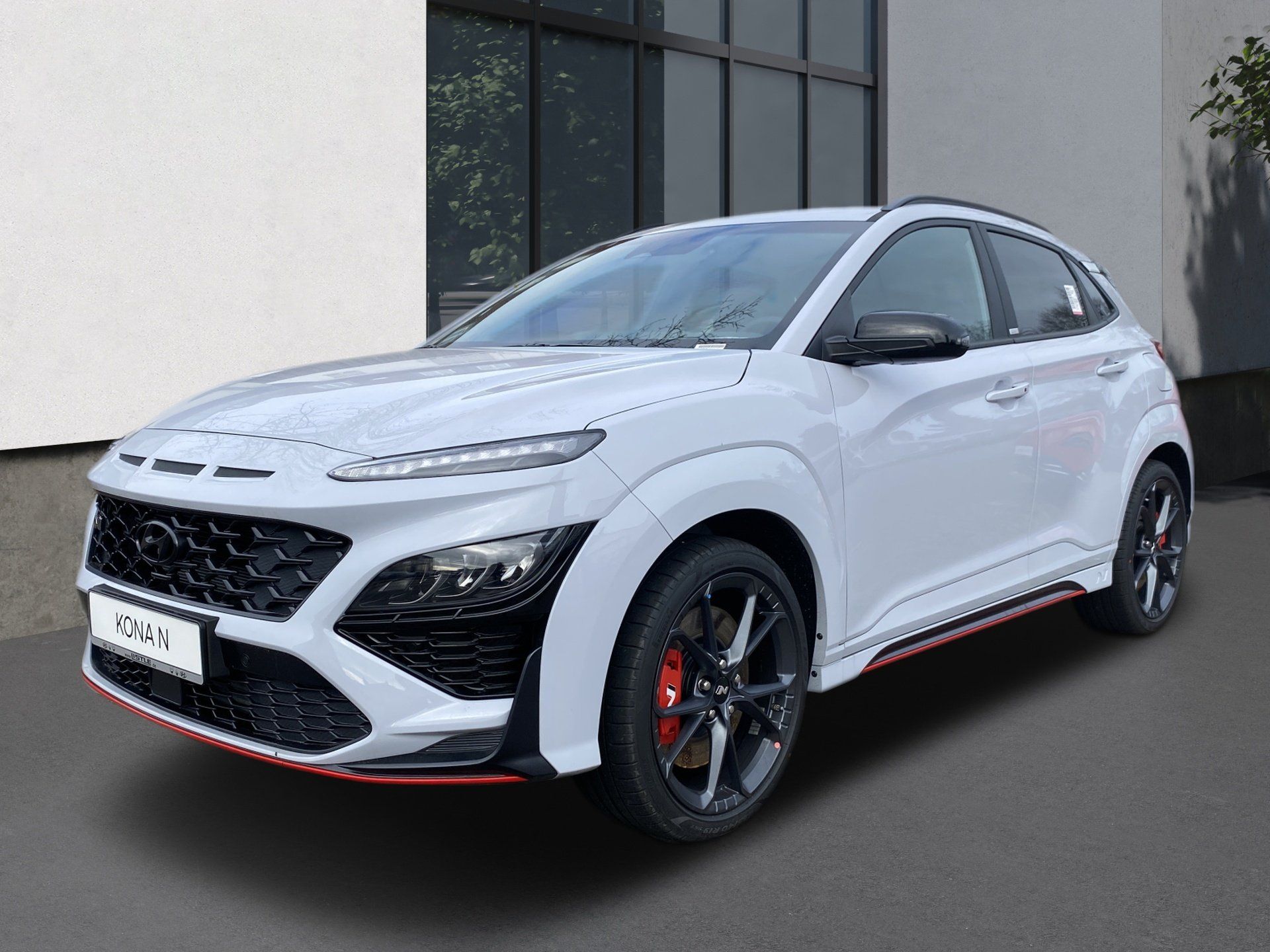 White sporty SUV parked outdoors against a building wall, with black rims and red trim accents