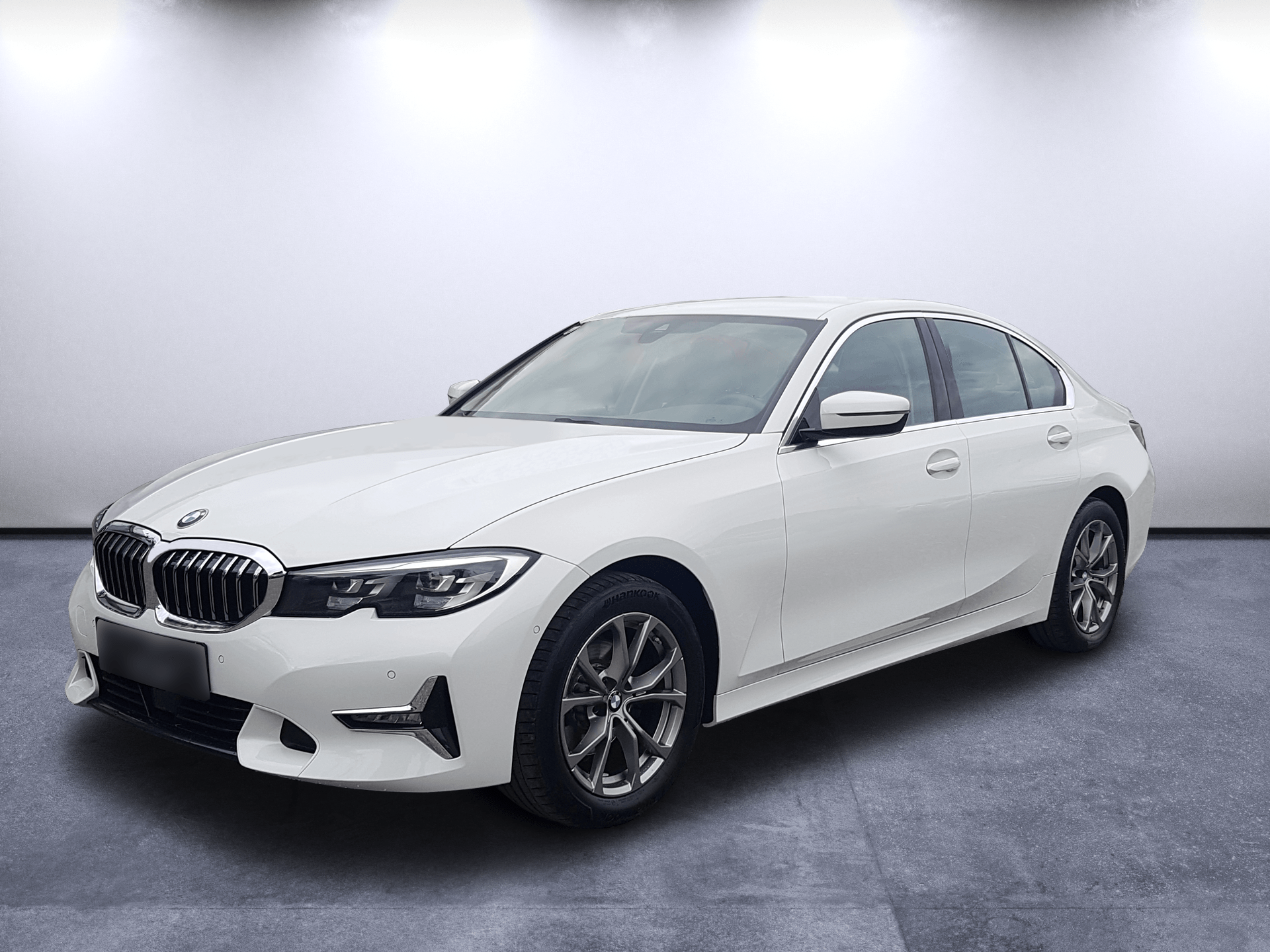 White BMW sedan in a studio on a gray floor, angled front-left view