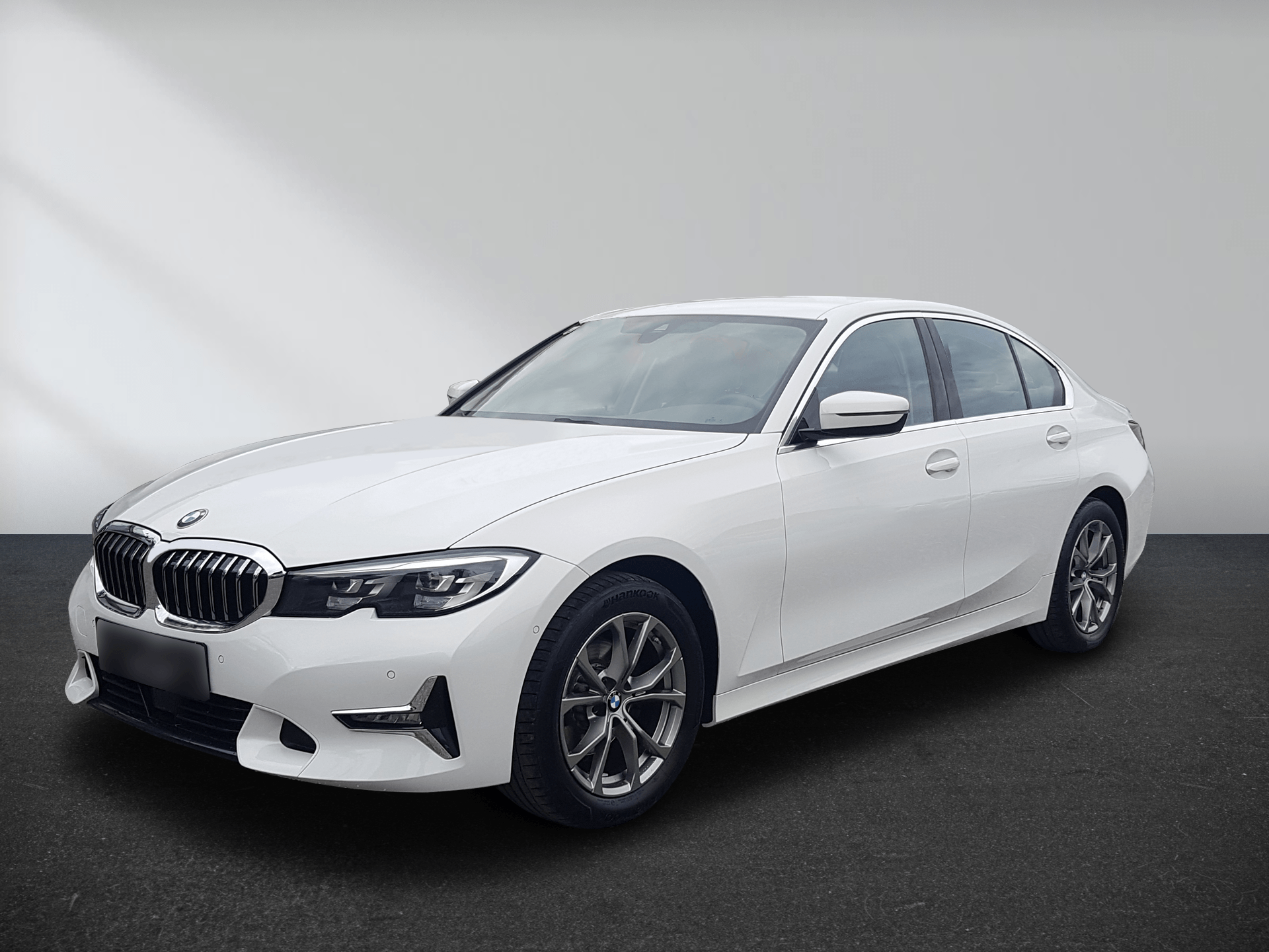 White BMW sedan parked in a studio against a plain gray background.