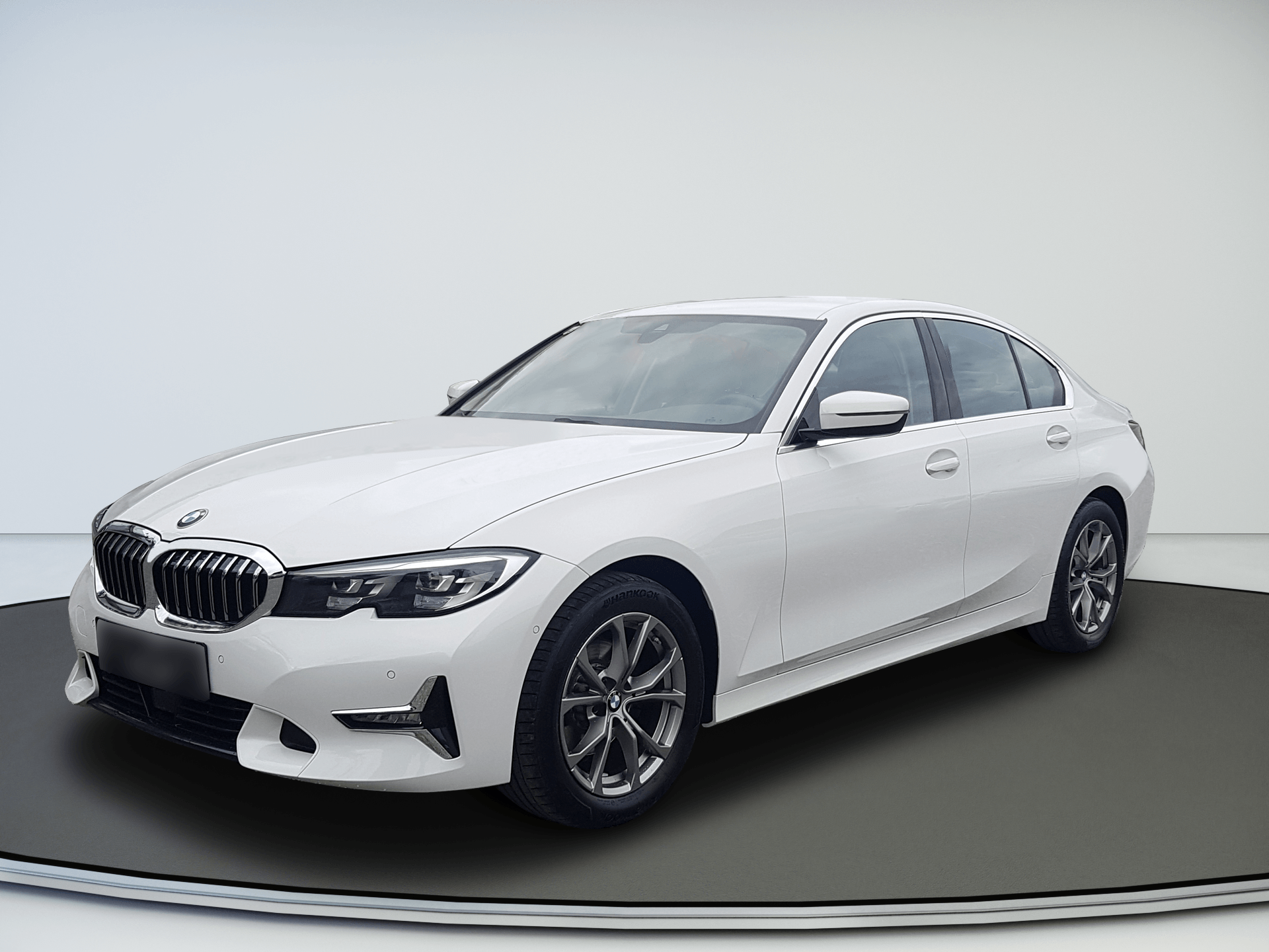 White BMW sedan in a studio setting, angled front-left on a gray floor