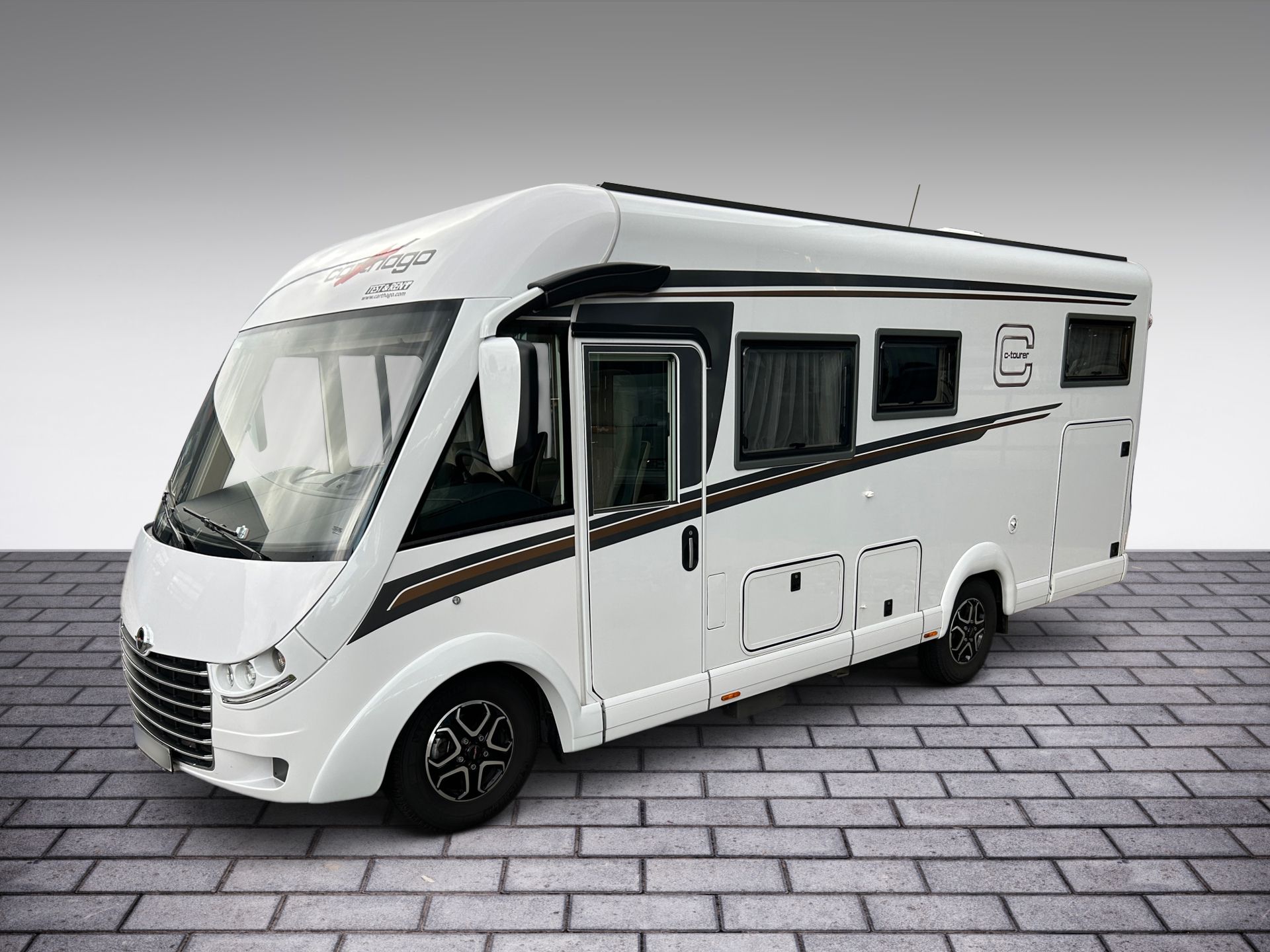 Biely obytný automobil na sivom kachličkovom povrchu, zobrazený v bočnom pohľade.