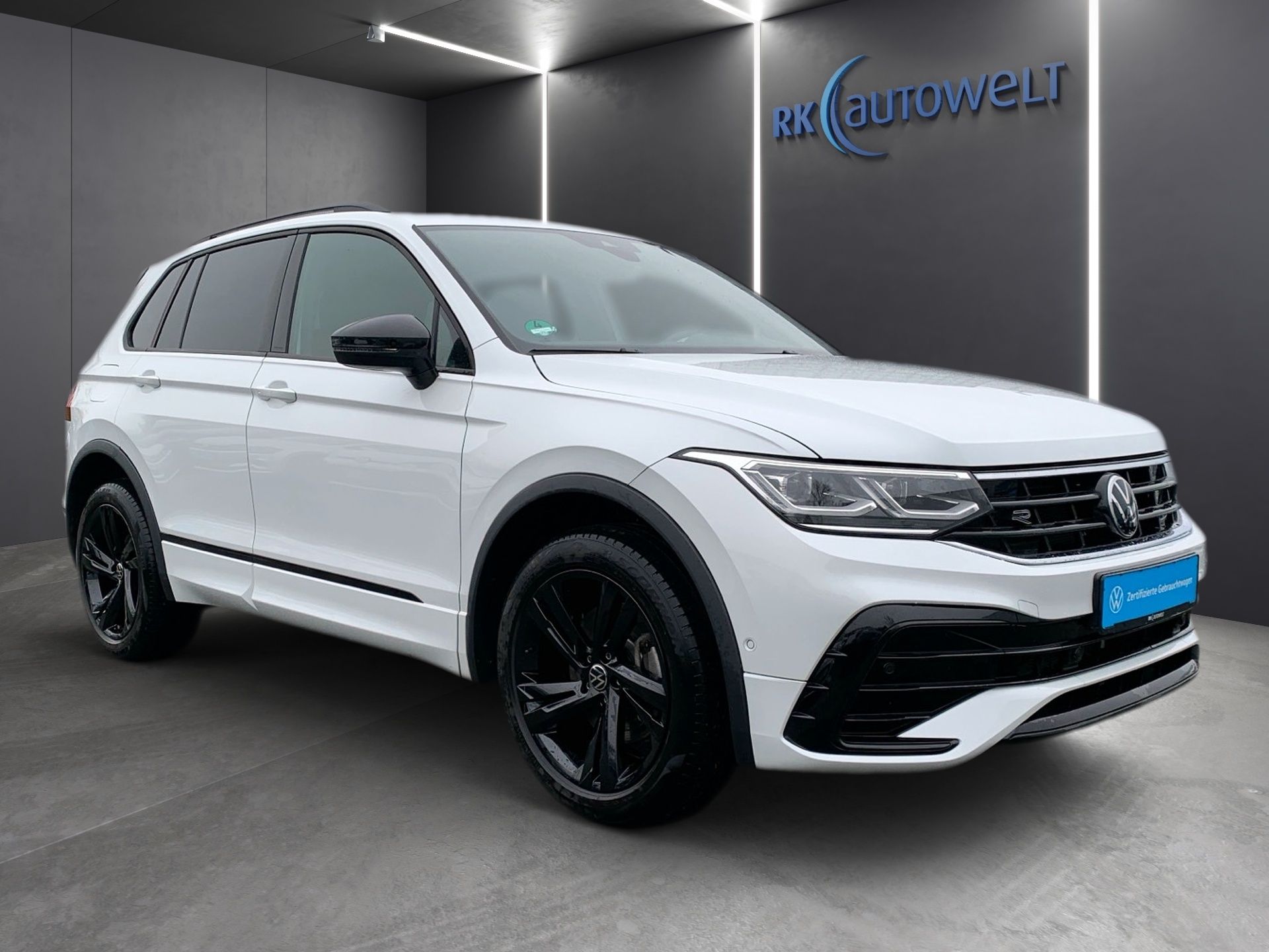 Biele SUV Volkswagen v showroome s čiernymi kolesami a modrým nápisom.