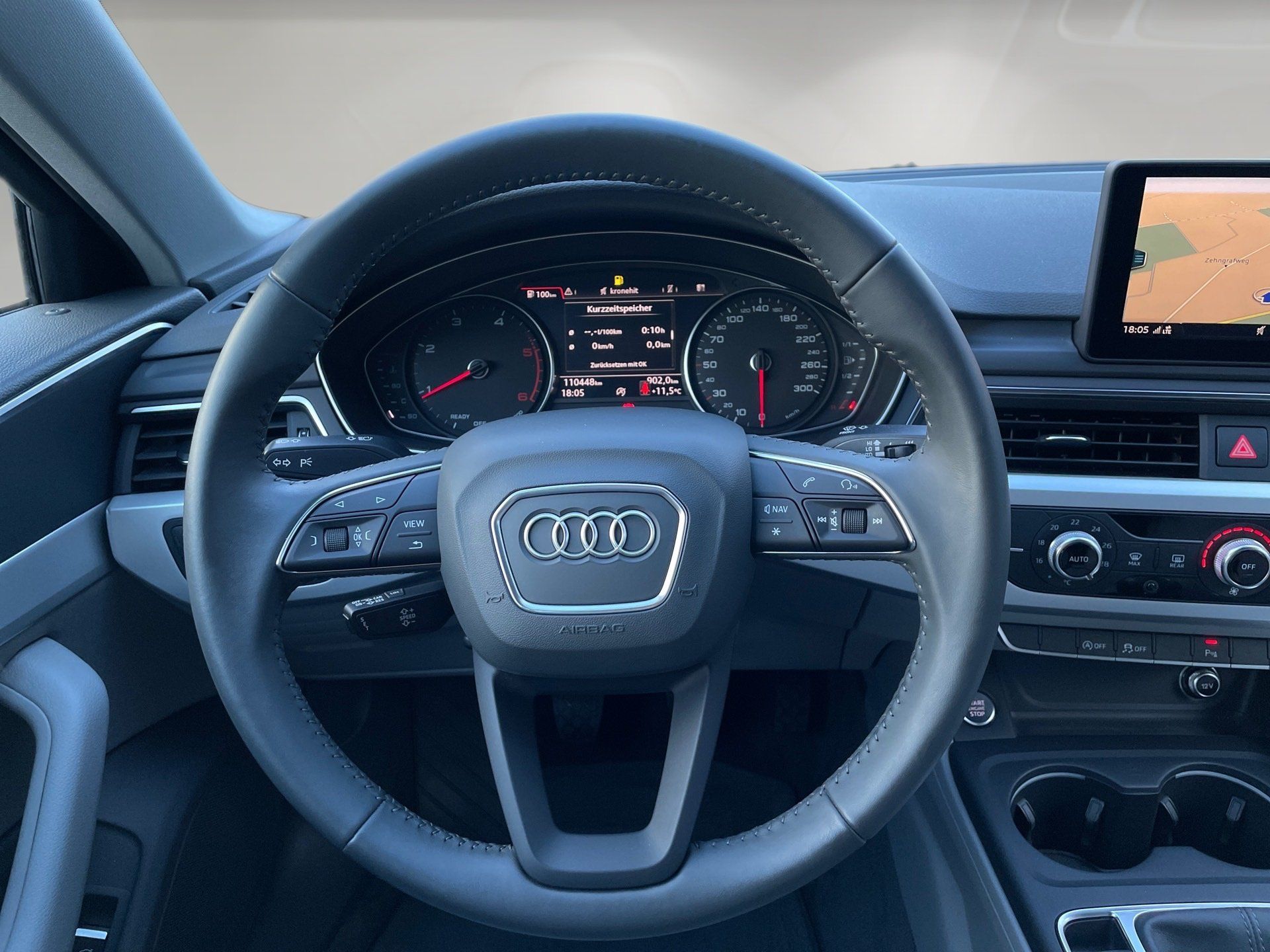 Audi steering wheel and dashboard viewed from the driver’s seat, with infotainment screen and climate controls.