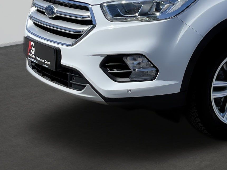 Front view of a white SUV with chrome grille and headlight detail on a road.