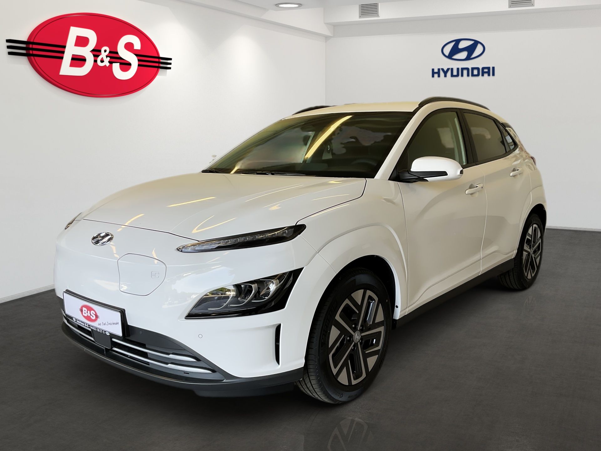 White Hyundai SUV displayed in a showroom, angled front view with B&S and Hyundai logos on the wall.