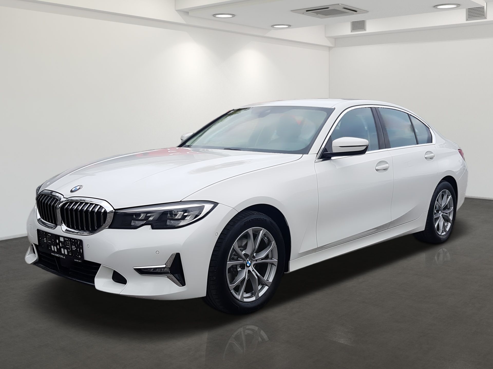 Biely sedan BMW zaparkovaný v showroome štúdia, pohľad zľava spredu