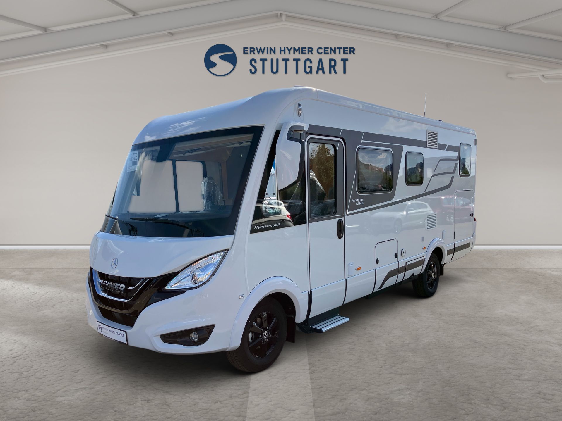 Biely minibus s veľkými oknami zaparkovaný v štúdiu, pohľad z ľavej prednej strany.