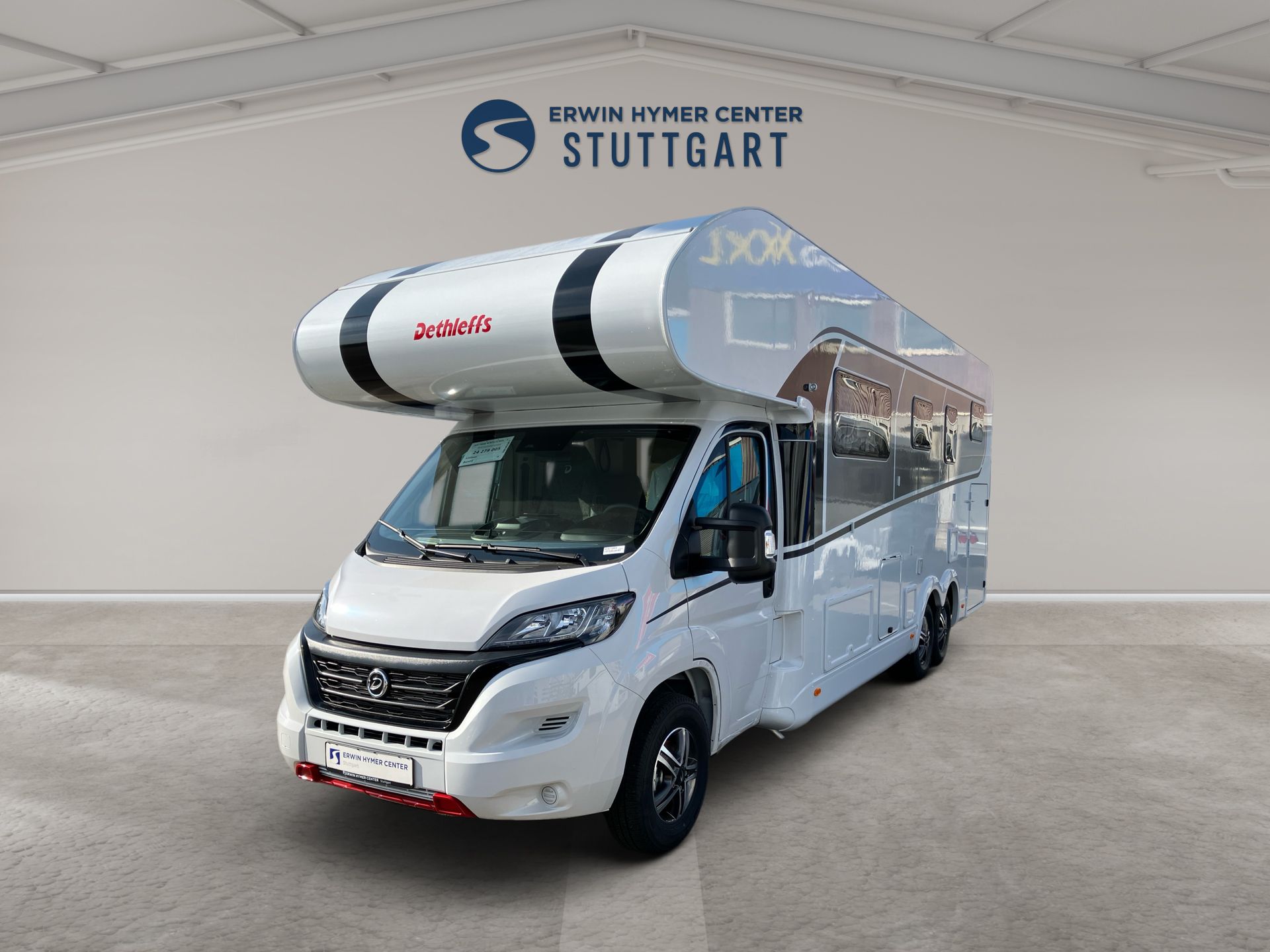 Biely obytný automobil s nafukovacím člnom na streche, zaparkovaný vo svetlom vnútornom štúdiu.