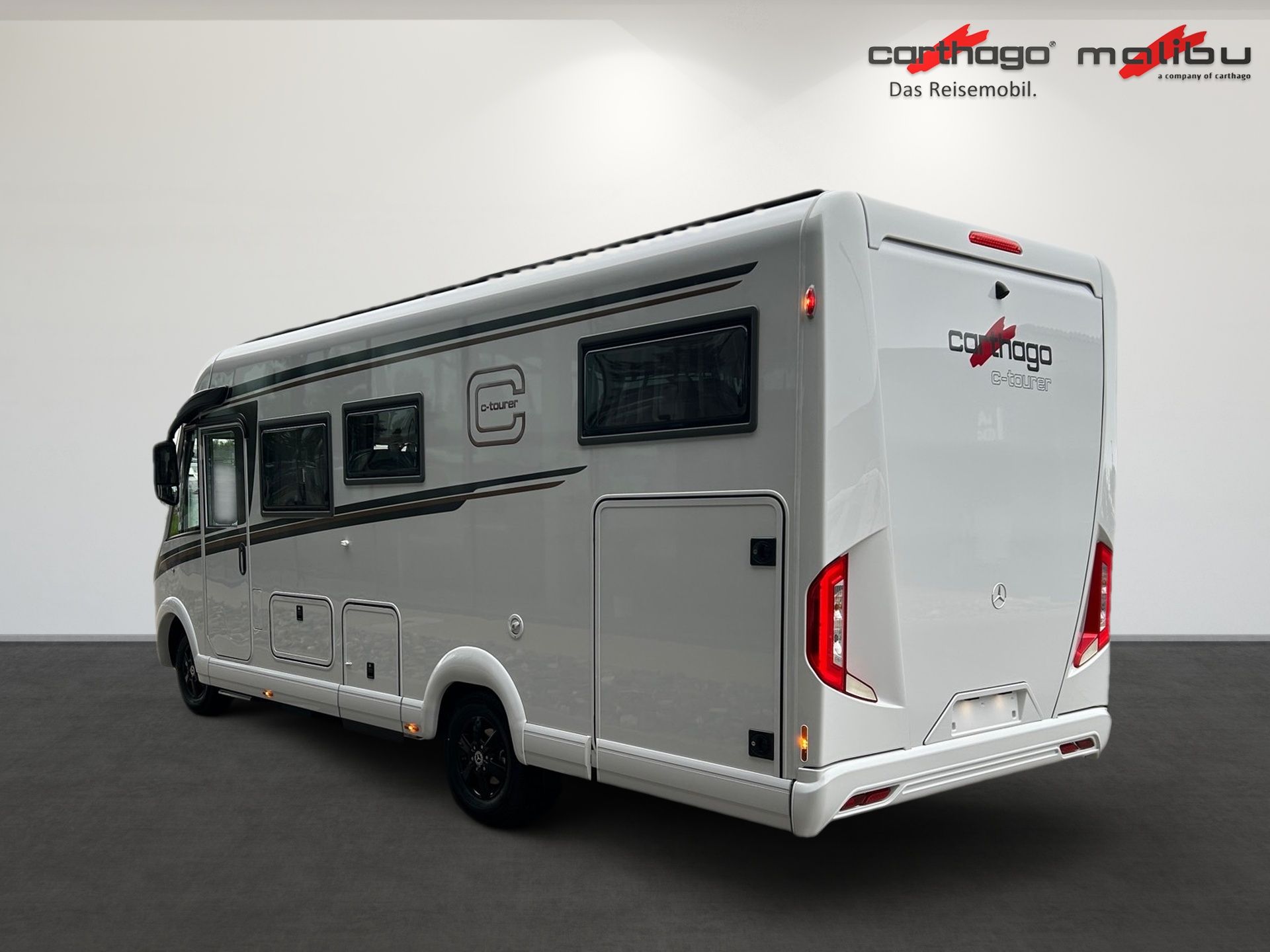 Ein weißes Wohnmobil steht vor einer weißen Wand.