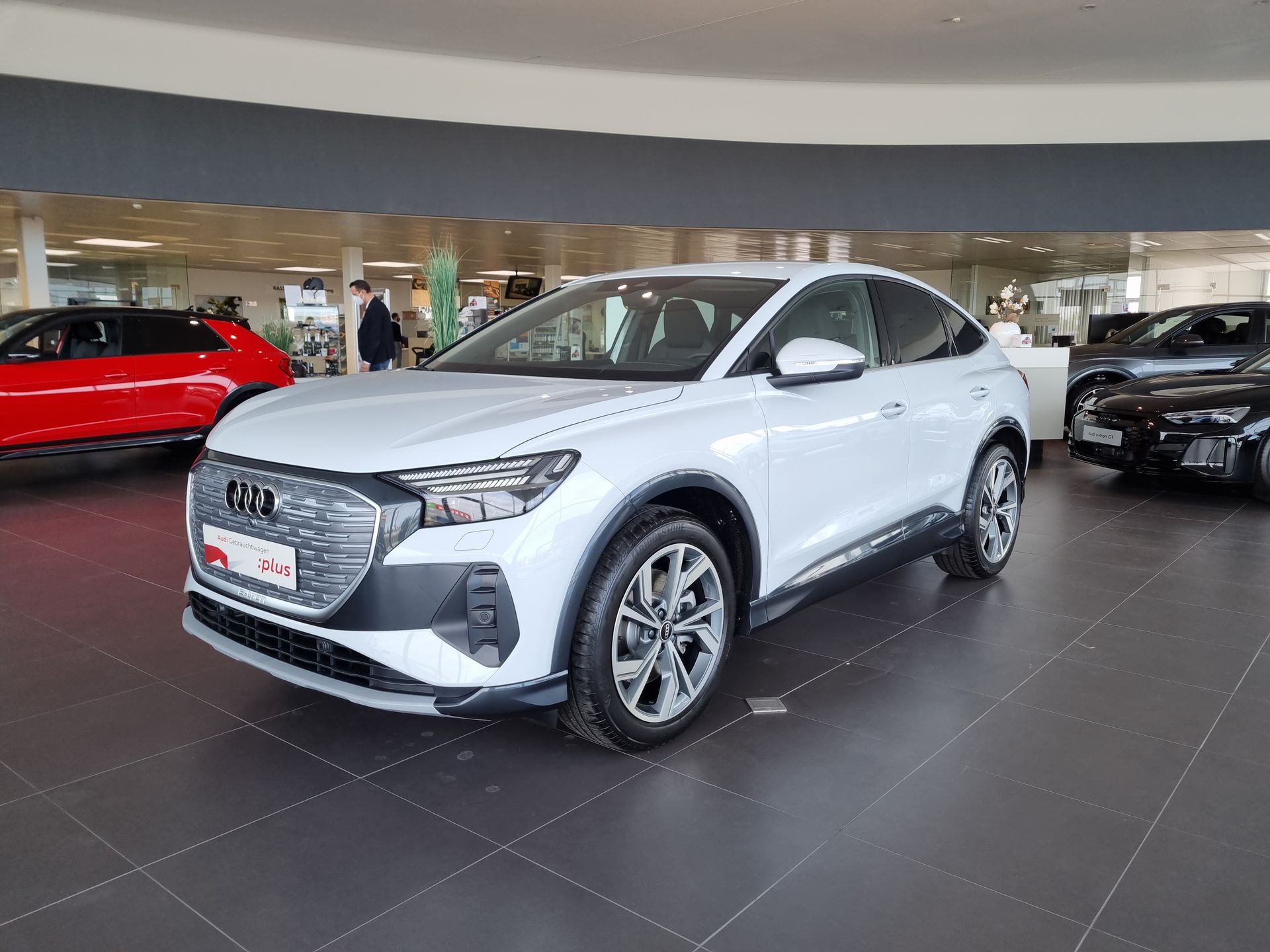 Silver Audi SUV displayed in a showroom, with other cars visible in the background.
