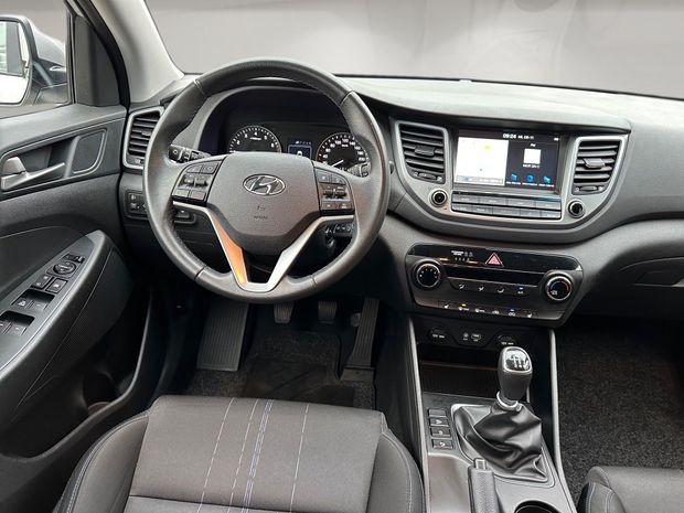 Der Innenraum eines Hyundai Tucson mit Lenkrad und Armaturenbrett - am Blick durch das Fenster ist zu erkennen, dass das Bild digital optimiert wurde.