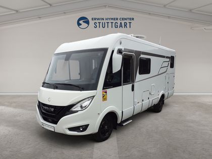Ein weißes Wohnmobil ist vor einem digitalen Ausstellungsraum geparkt.