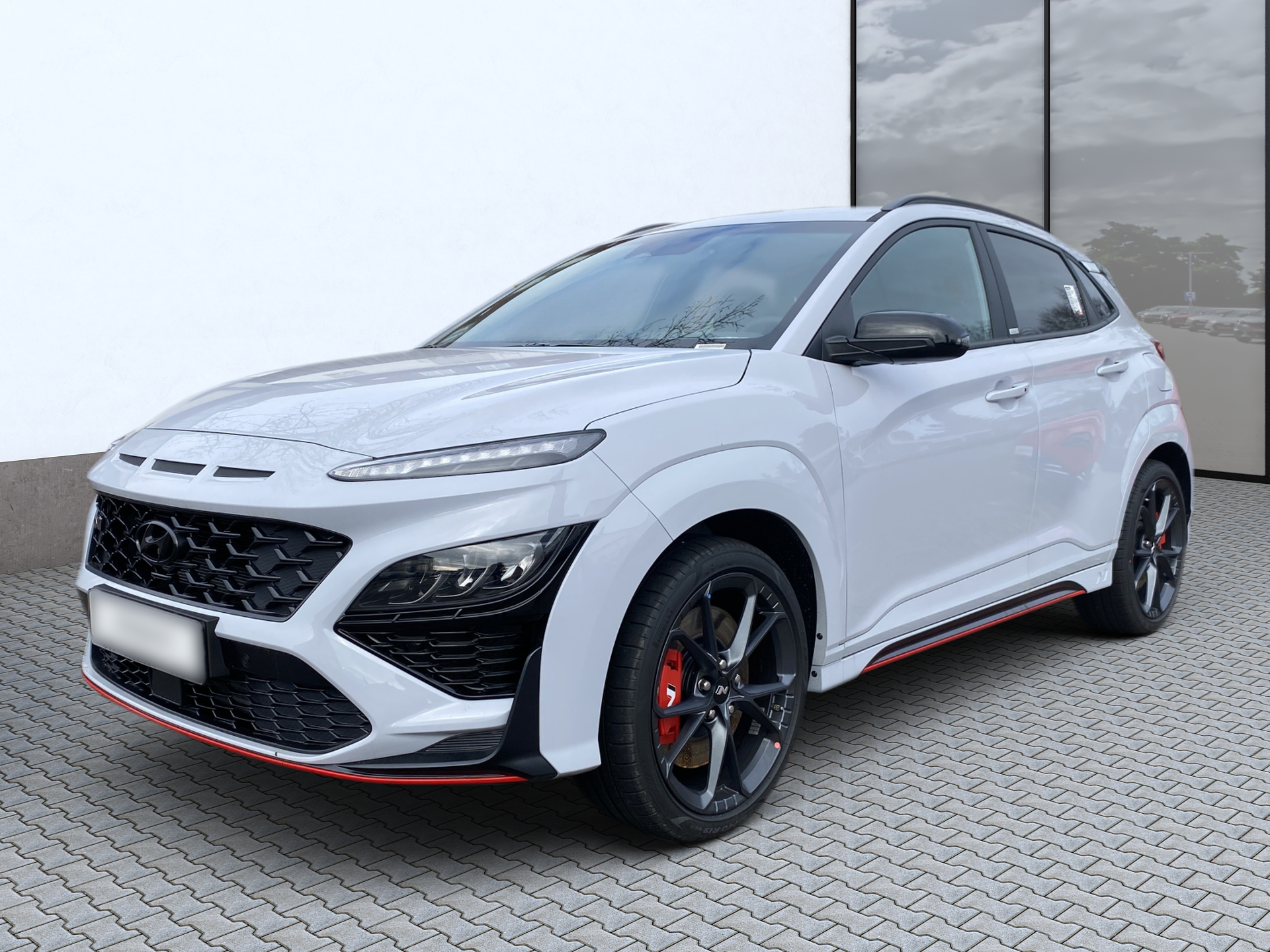 White sporty SUV parked on a paved lot, front three-quarter view, with black trim and red accents.