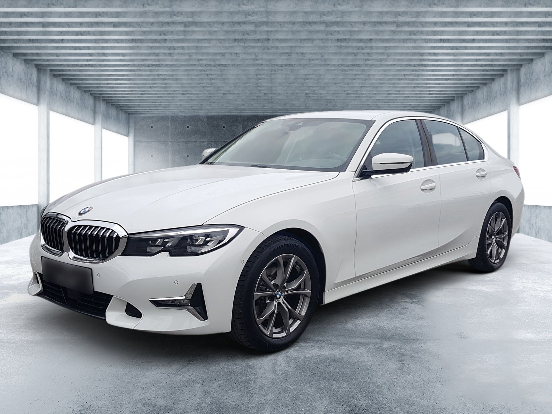 White BMW sedan parked in a bright showroom, front-left view