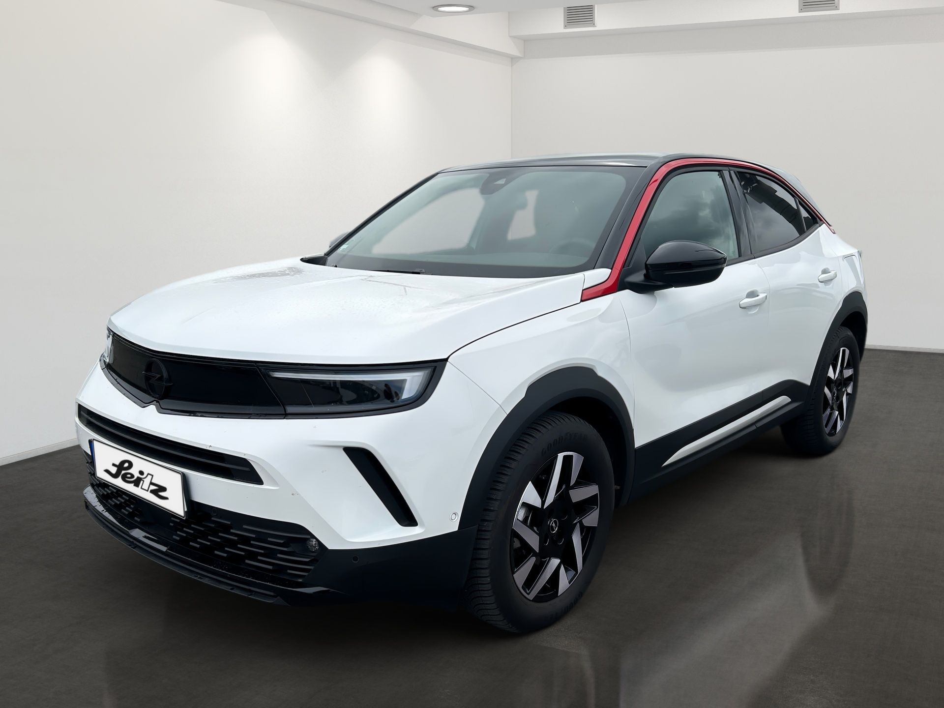 White SUV with black trim displayed in a studio showroom, front-left view