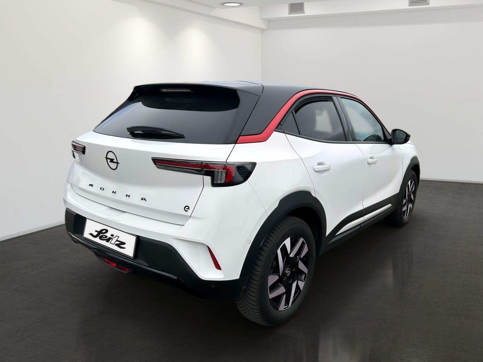 White and black compact SUV with red accents, rear three-quarter view in a showroom