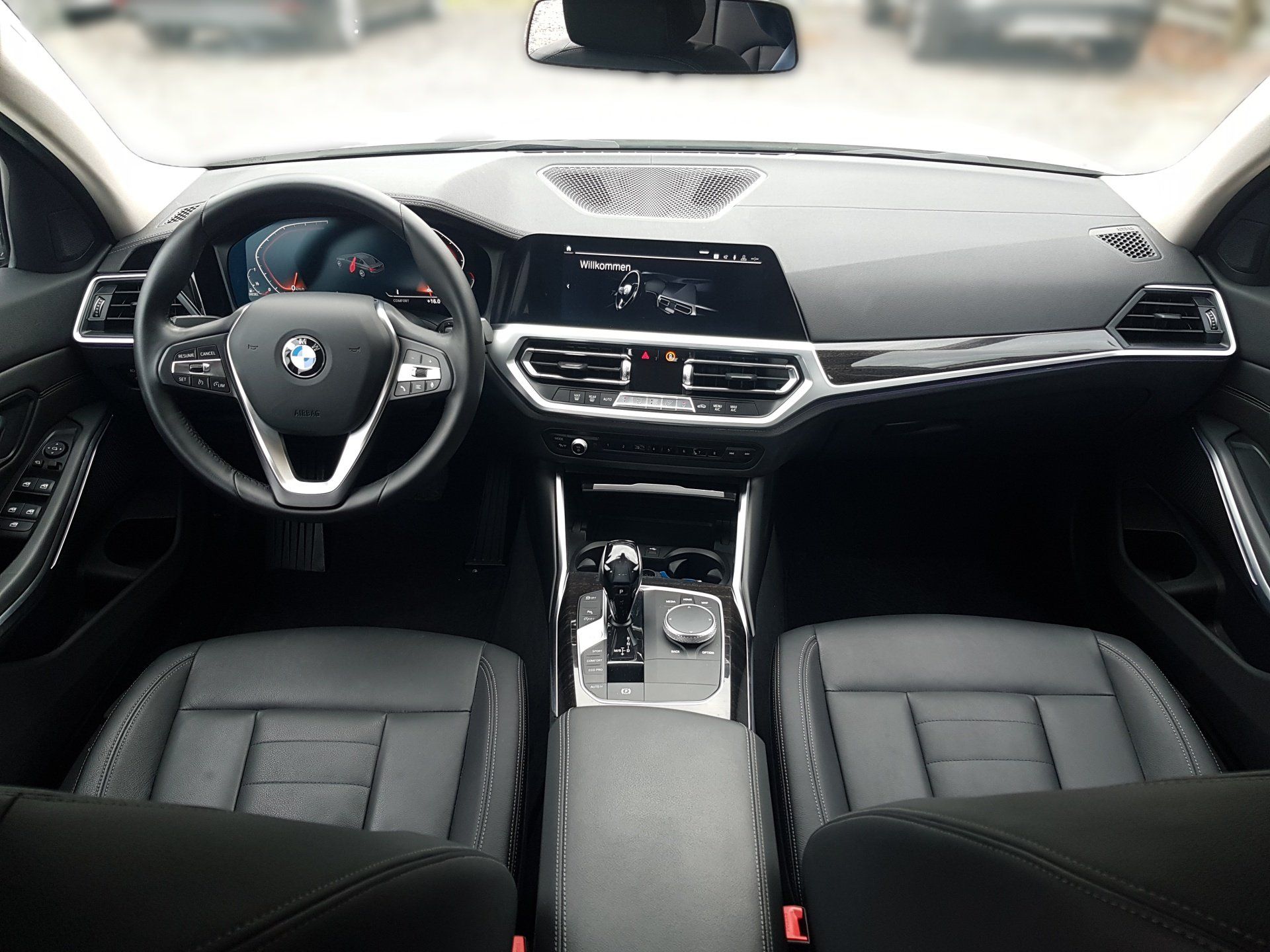Pohľad do interiéru auta s čiernou palubnou doskou BMW, volantom, stredovou konzolou a prednými sedadlami