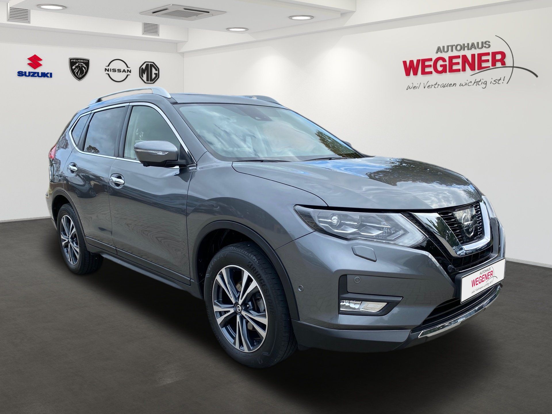 Gray Nissan SUV in a showroom with Wegener Automotive branding on the wall
